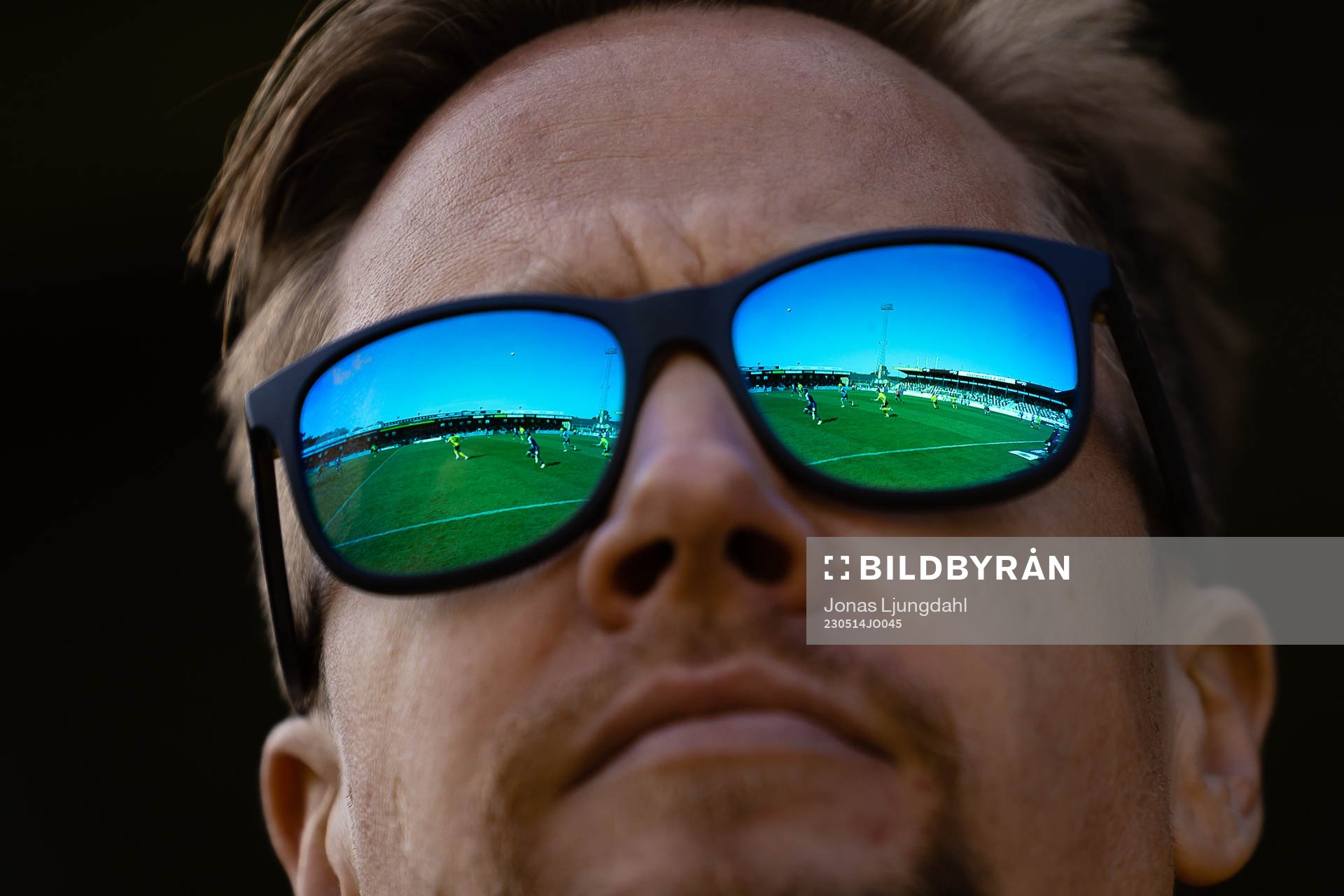 Strandvallens spelplan speglas i ett par solglasögon under fotbollsmatchen i Allsvenskan mellan Mjällby och Sirius den 14 maj 2023 i Hällevik.