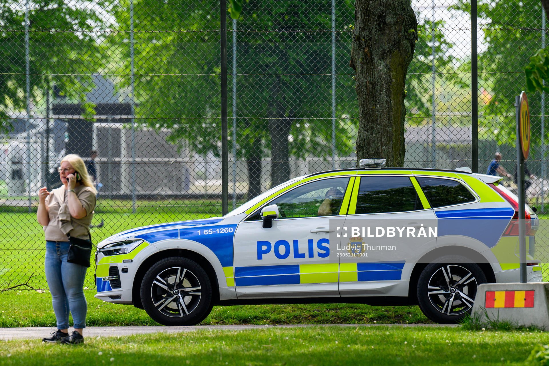 En kvinna pratar i telefon bredvid en polisbil