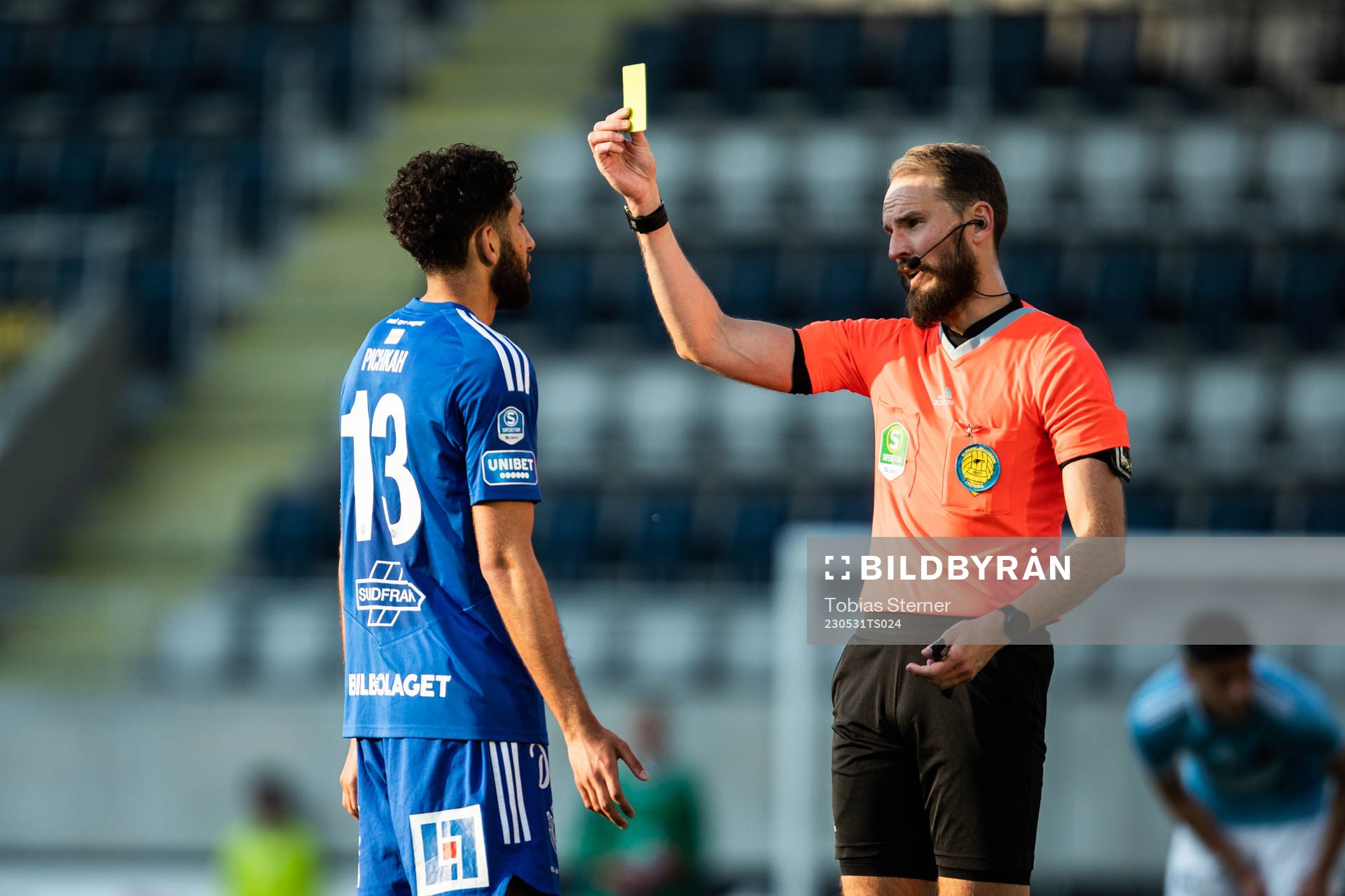 Domare Andreas Dufva-Johansson delar ut ett gult kort till