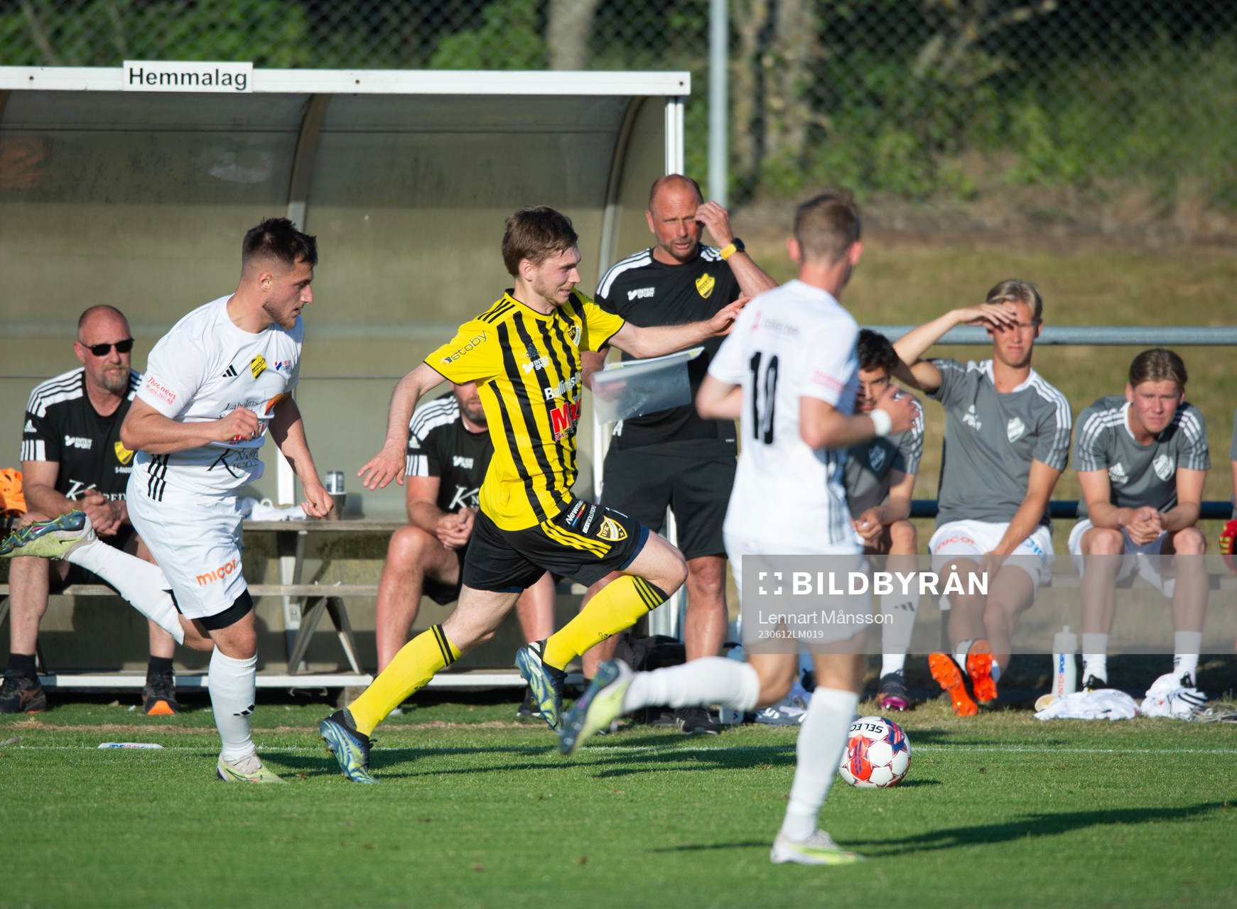 IFK Hässleholms Edvin Nilsson flyger förbi Laholms bänk med tränaren Jonas Axeldal som åskådare i matchen i Svenska Cupen mellan Laholm och IFK Hässleholm i Laholm 12 juni 2023.
