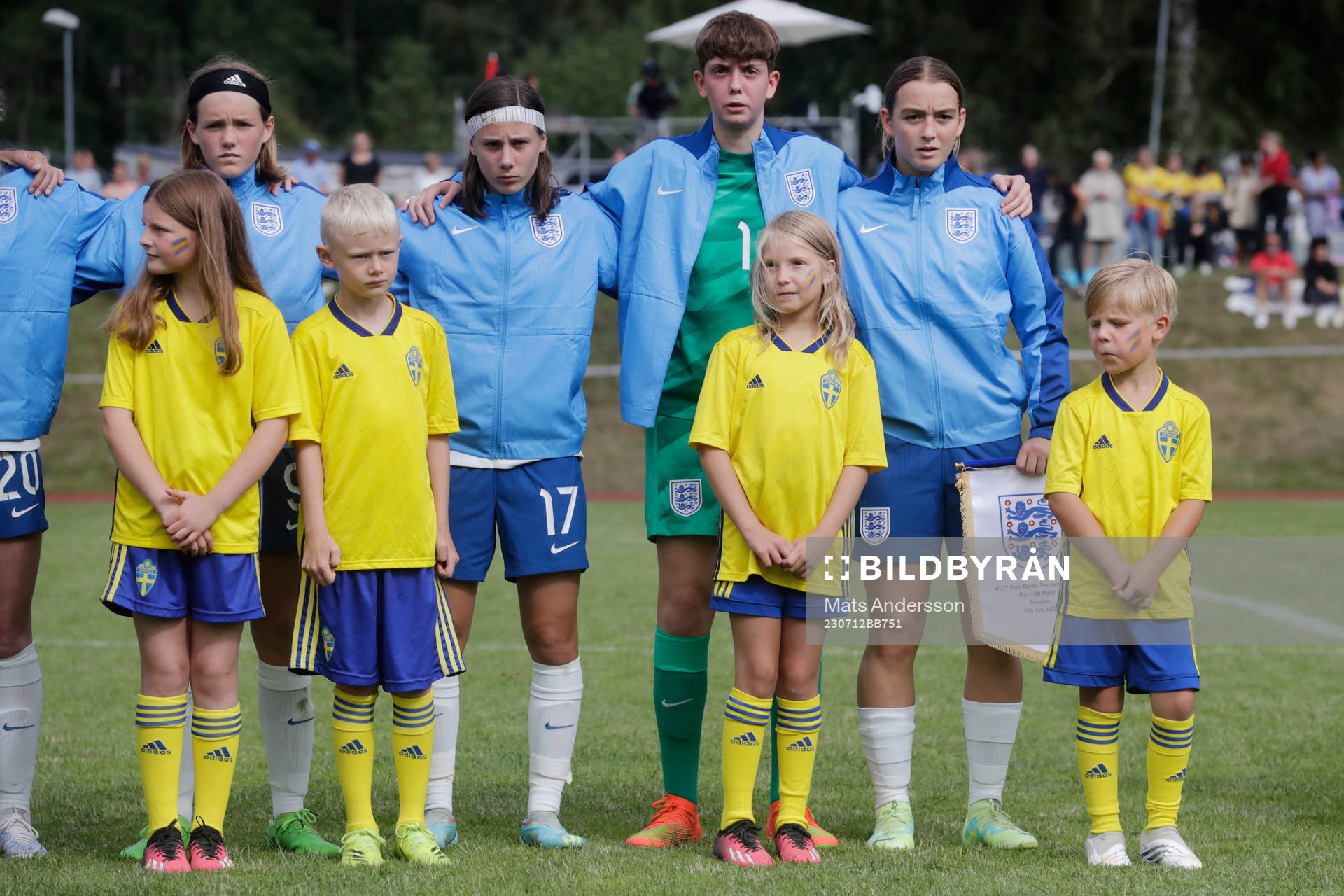 Maskotar i landslagsdress vid lineup innan fotbollsmatchen