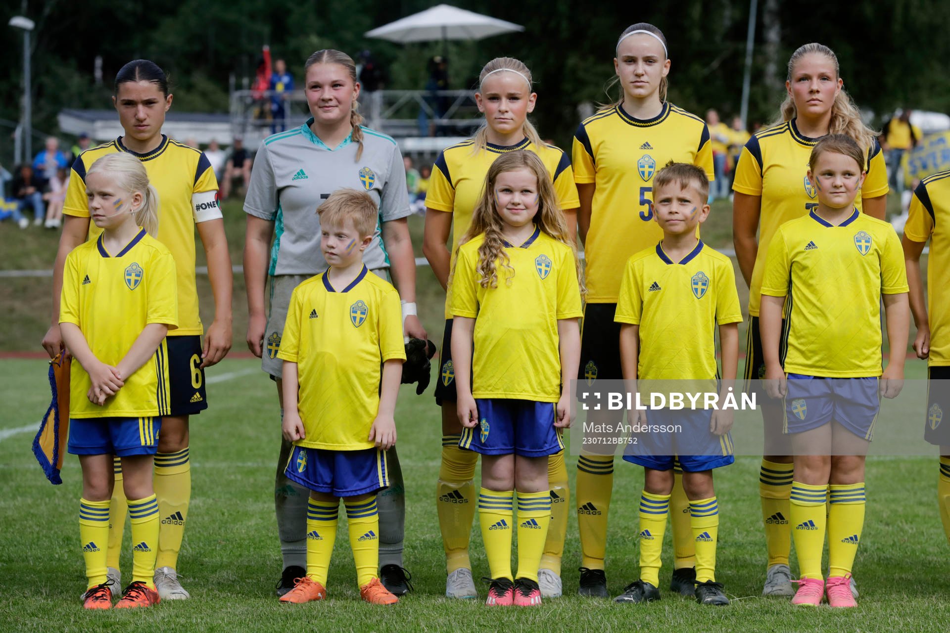 Maskotar i landslagsdress vid lineup innan fotbollsmatchen