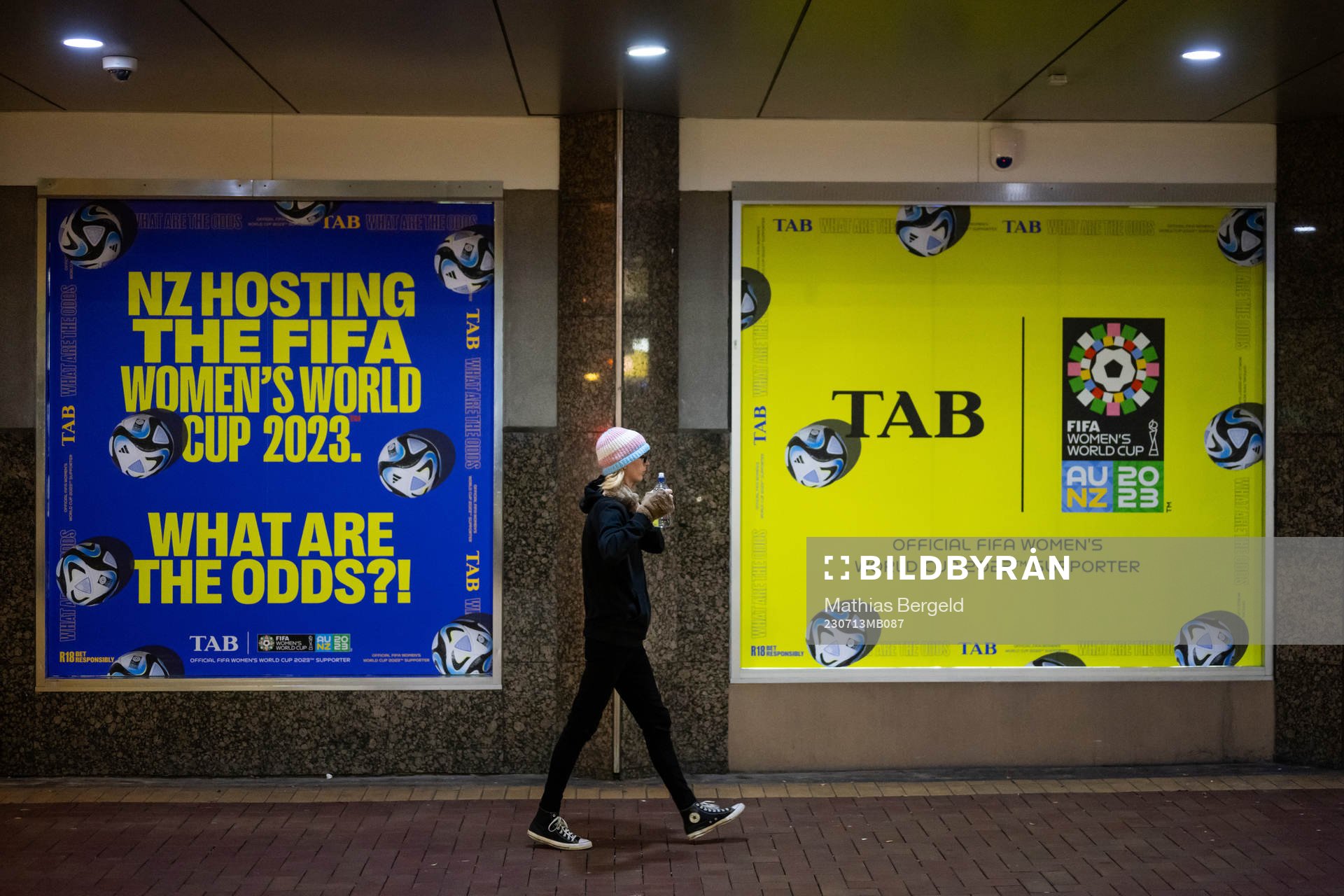 A woman walks past signs with adds about the FIFA Women's