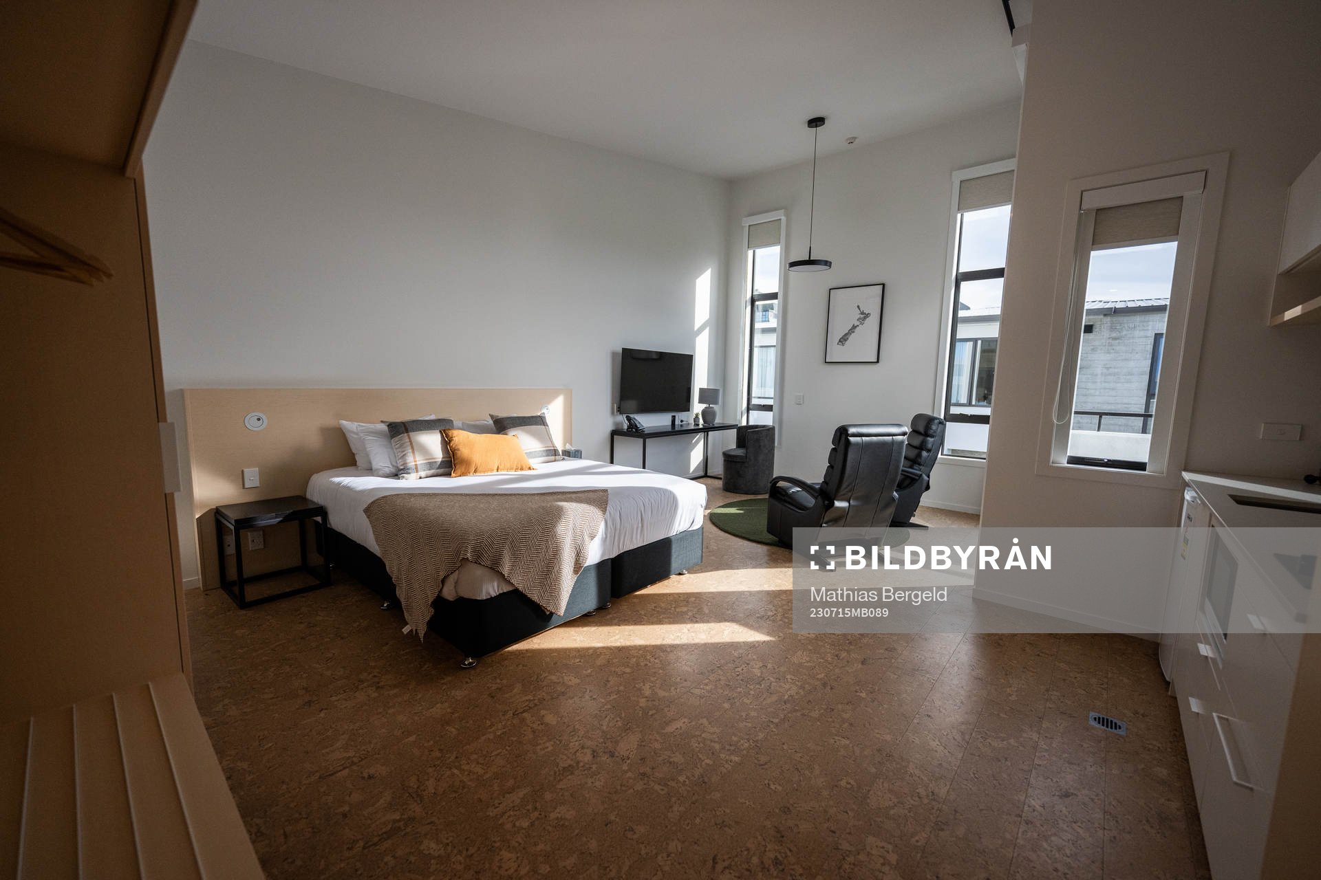The bed, TV area, and, kitchen in an apartment