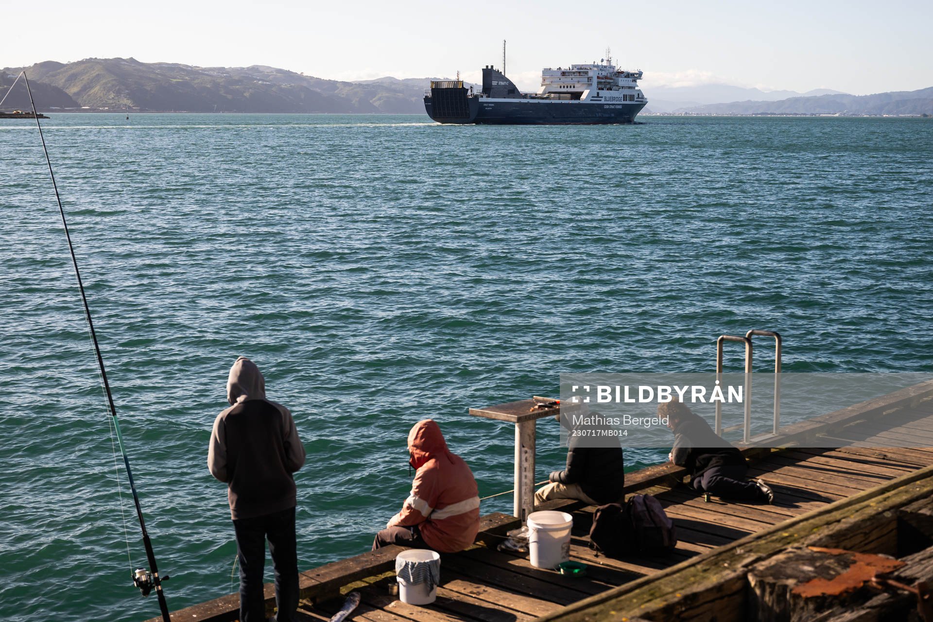 People fish as a ferry pass by