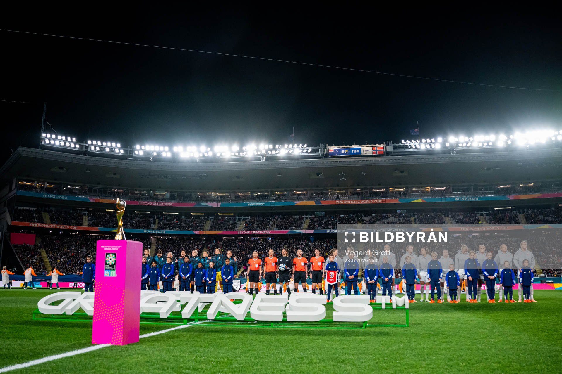 Players of both teams line up behind the trophy