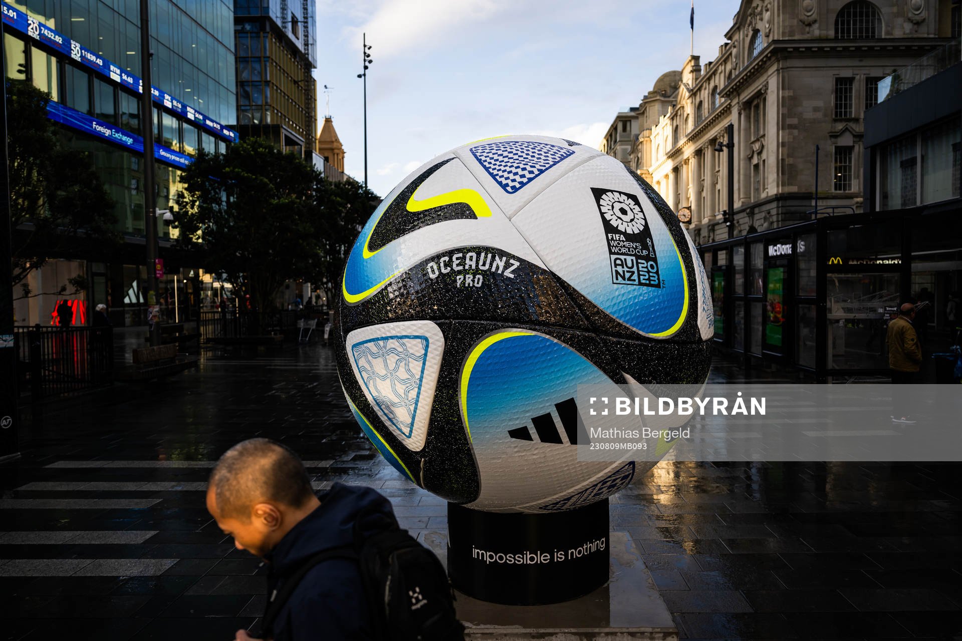People walk past a replica of the official match ball
