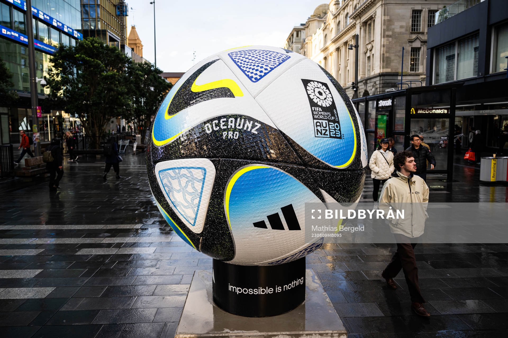People walk past a replica of the official match ball