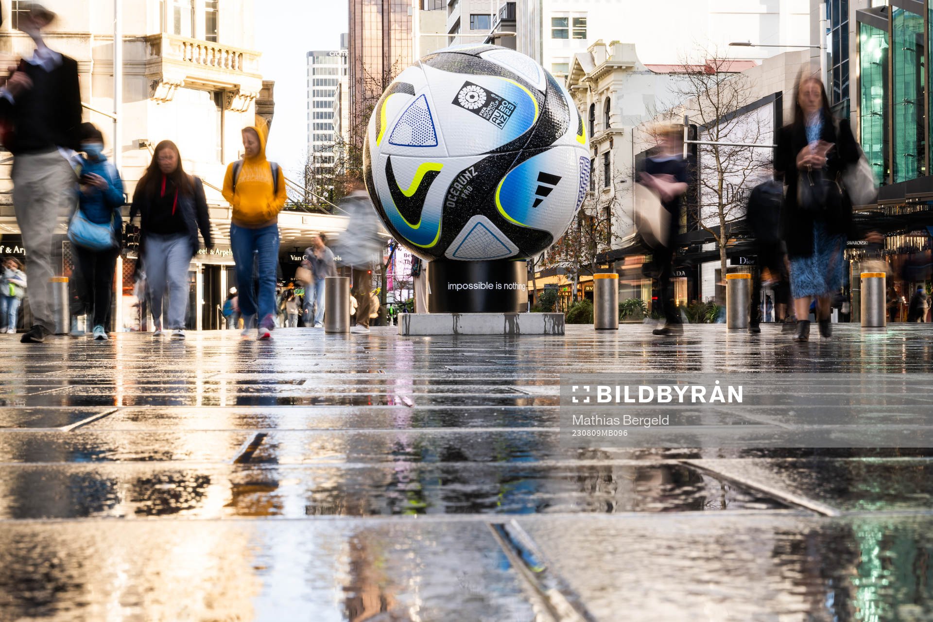 People walk past a replica of the official match ball