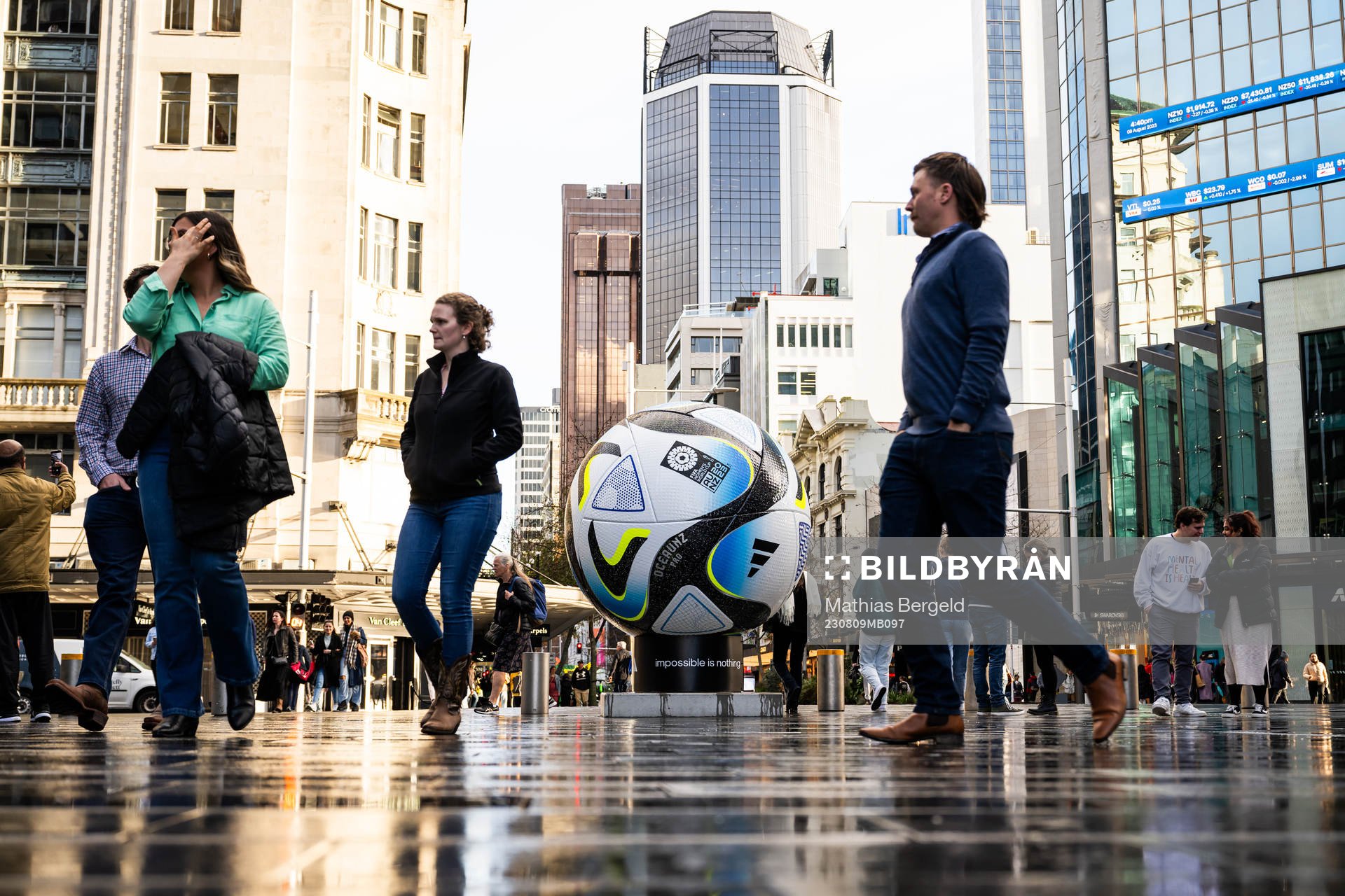 People walk past a replica of the official match ball