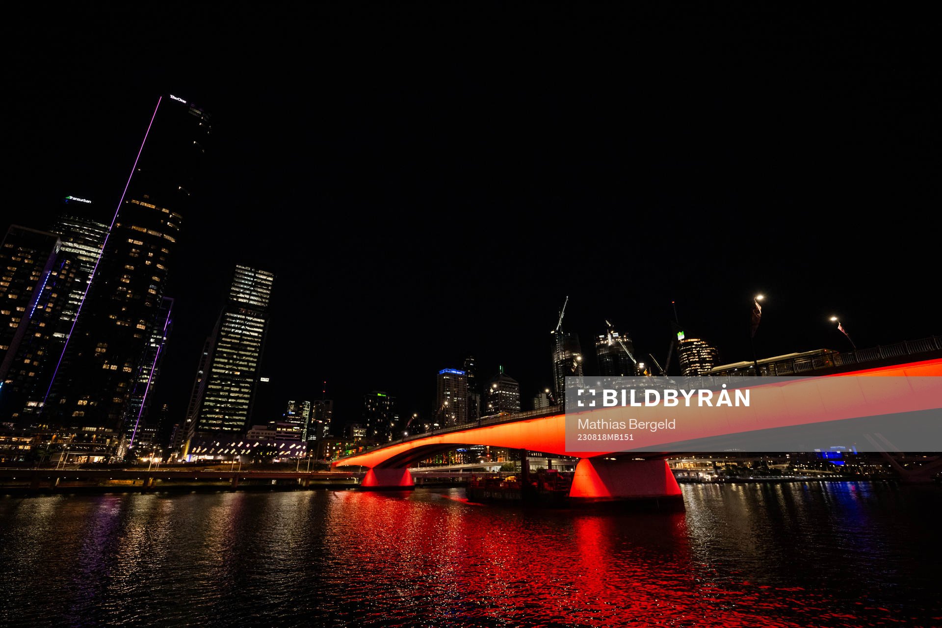 A bridge, lit in red, over Yarra River