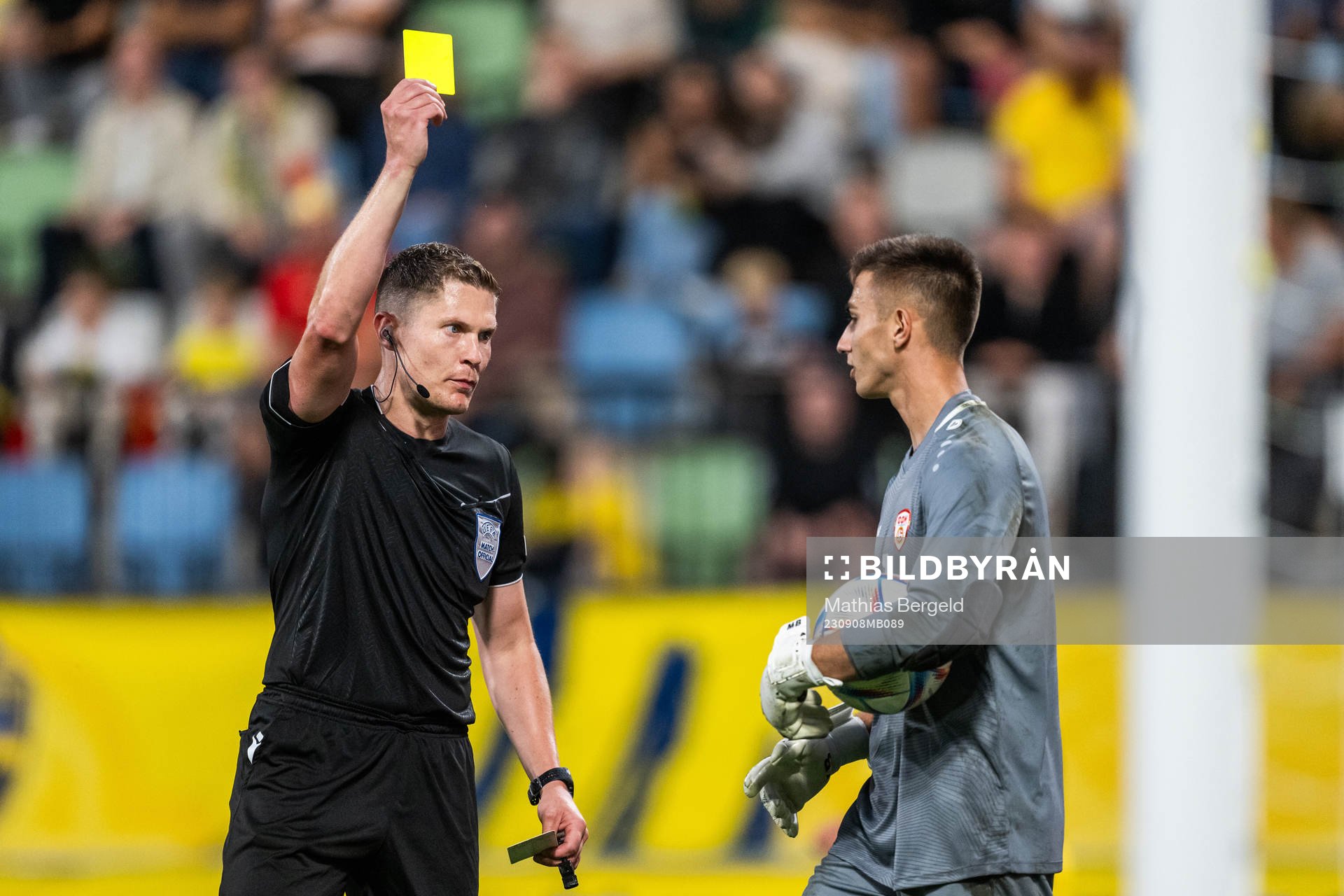 Referee David Dickinson shows the yellow card to goalkeeper
