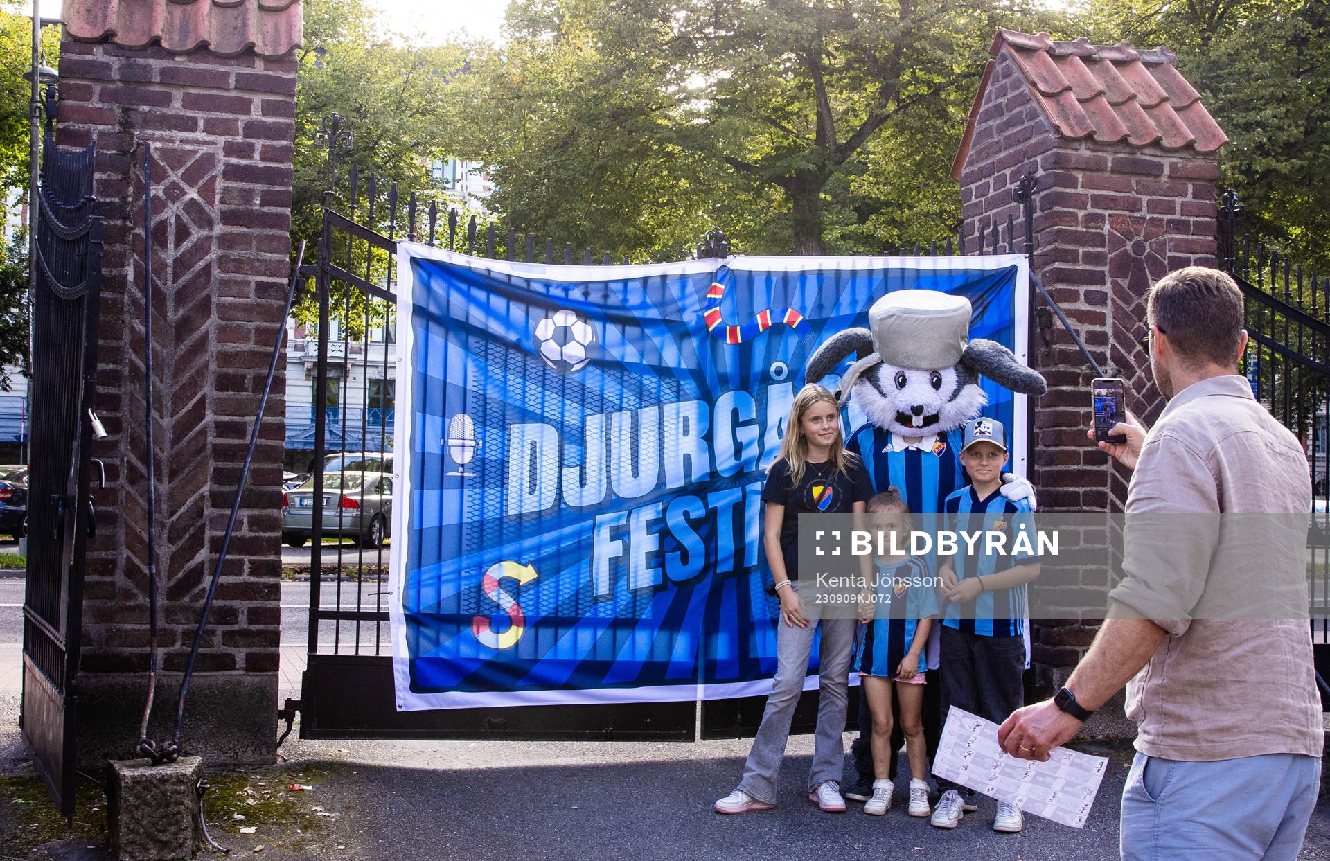 Unga Djurgårdensupportar fotograferas med en maskot
