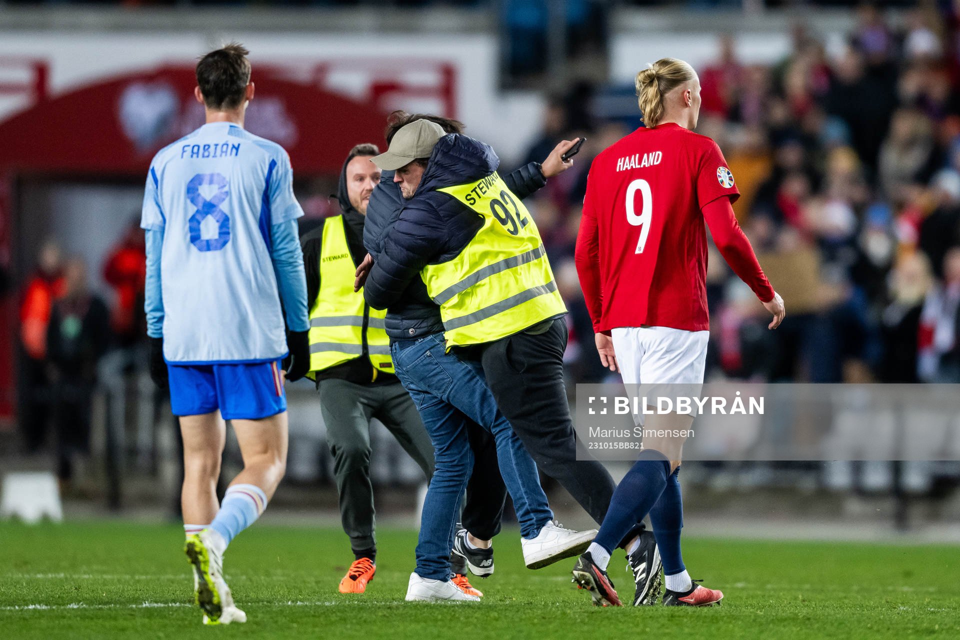 A steward is taking care of a pitch invader