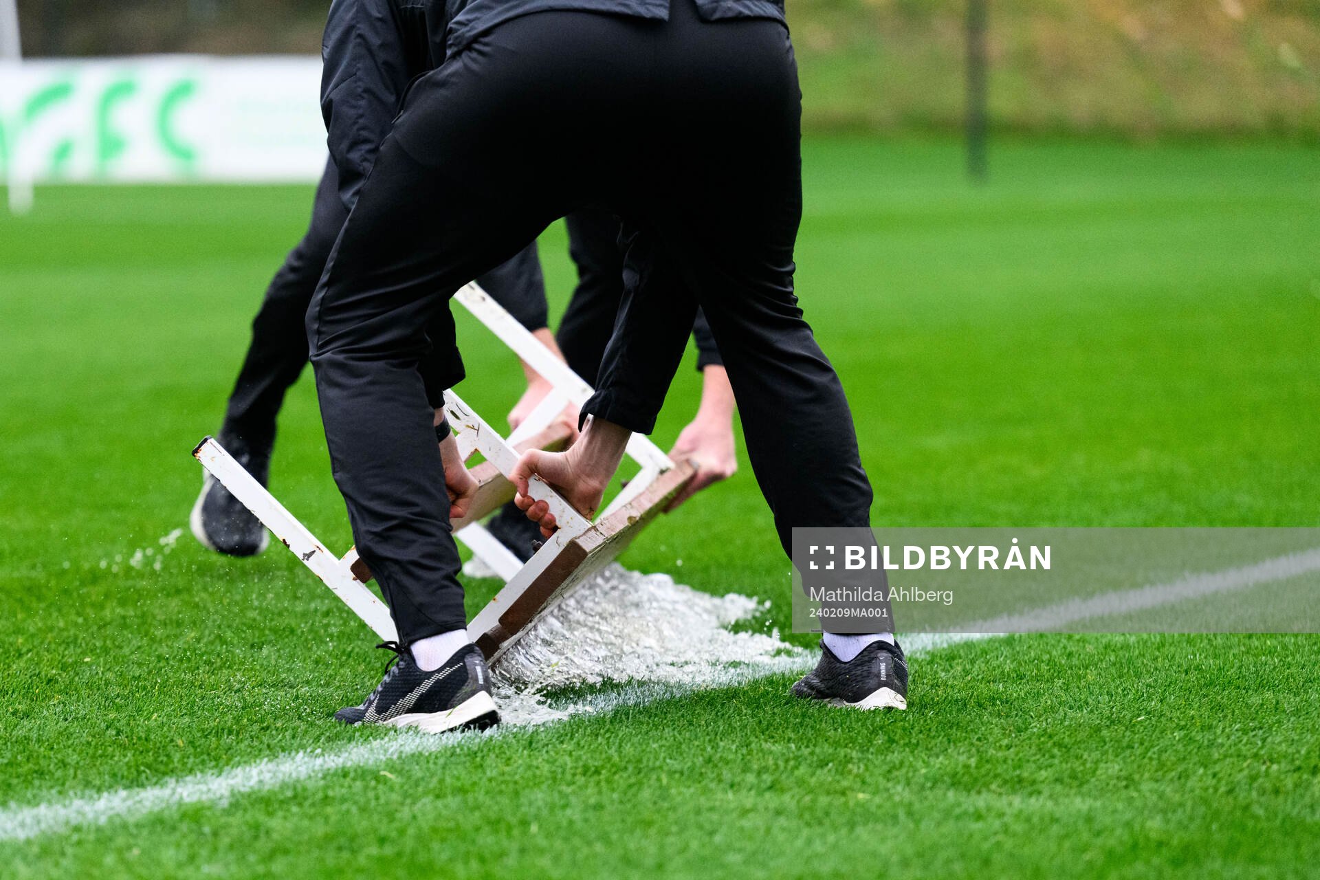 Staff of Brann shuffels water of the pitch