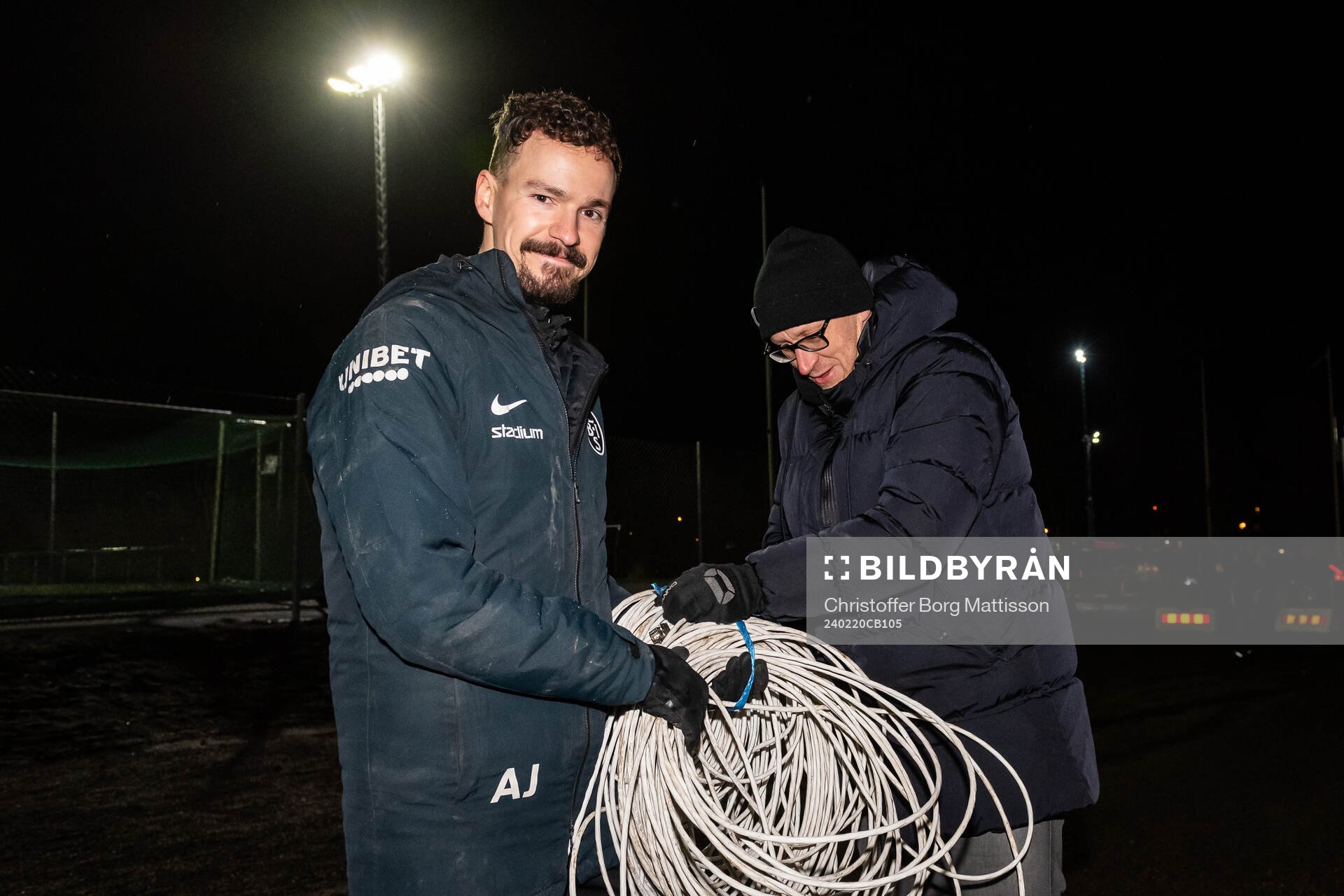 Landskronas assisterande tränare Amir Jakirlic och sportchef Billy Magnusson tar hand om en nätverkskabel till TV-sändningen efter träningsmatchen i fotboll mellan Landskrona BOIS och Ängelholm den 20 februari 2024 i Landskrona.
