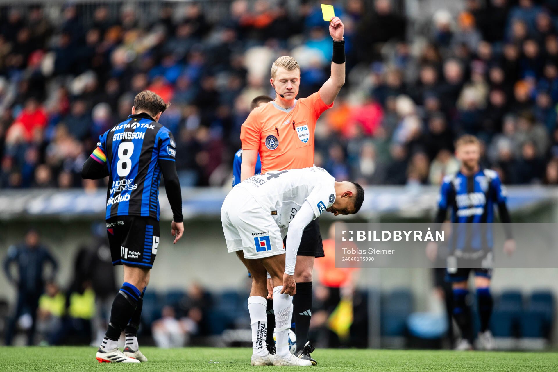 Domare Adam Ladebäck delar ut ett gult kort till Halmstads