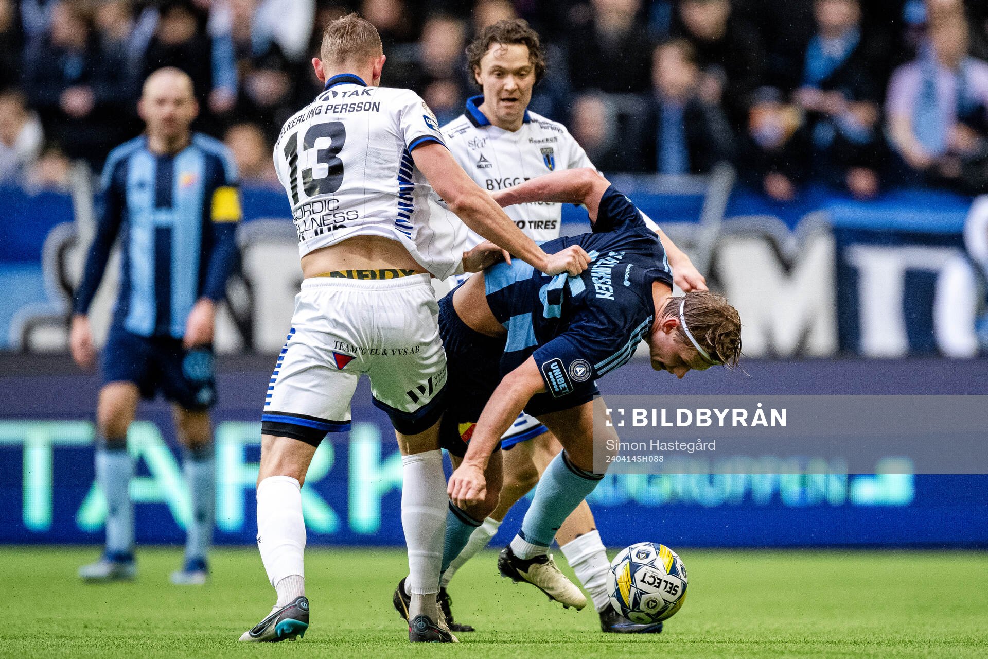 Sirius Jakob Voelkerling Persson och Herman Sjögrell i en kamp mot Djurgårdens Tobias Gulliksen under fotbollsmatchen i Allsvenskan mellan Djurgården och Sirius den 14 april 2024 i Stockholm.