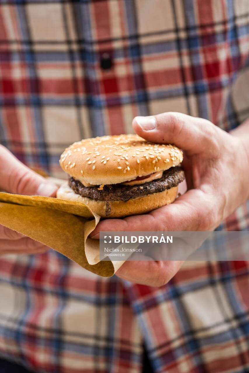 En person håller upp en hamburgare innan fotbollsmatchen i