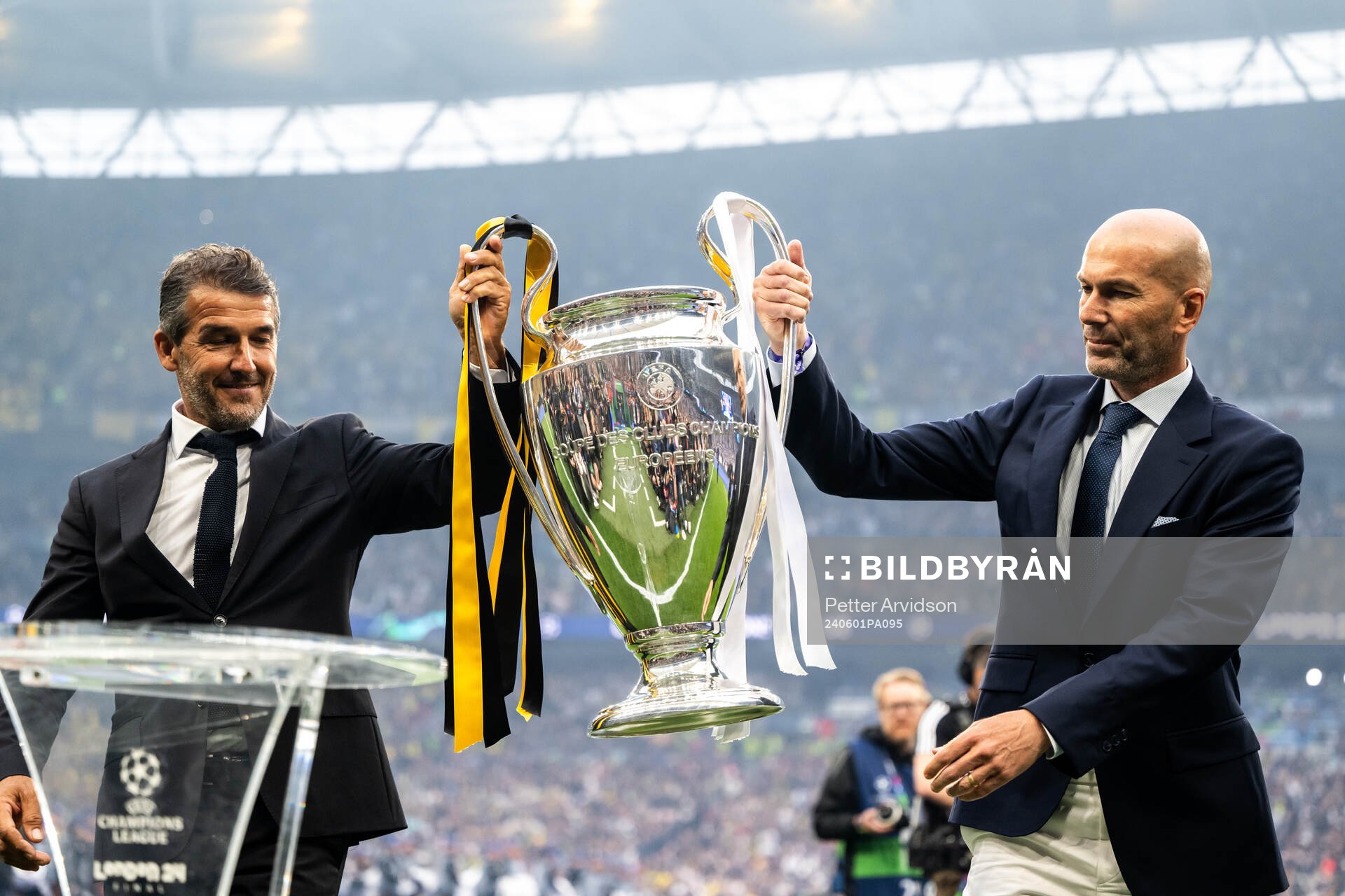 Former players Karl Heinz Riedle and Zinedine Zidane carry the Champions League trophy onto the pitch ahead of the UEFA Champions League final between Dortmund and Real Madrid on June 1, 2024 in London.