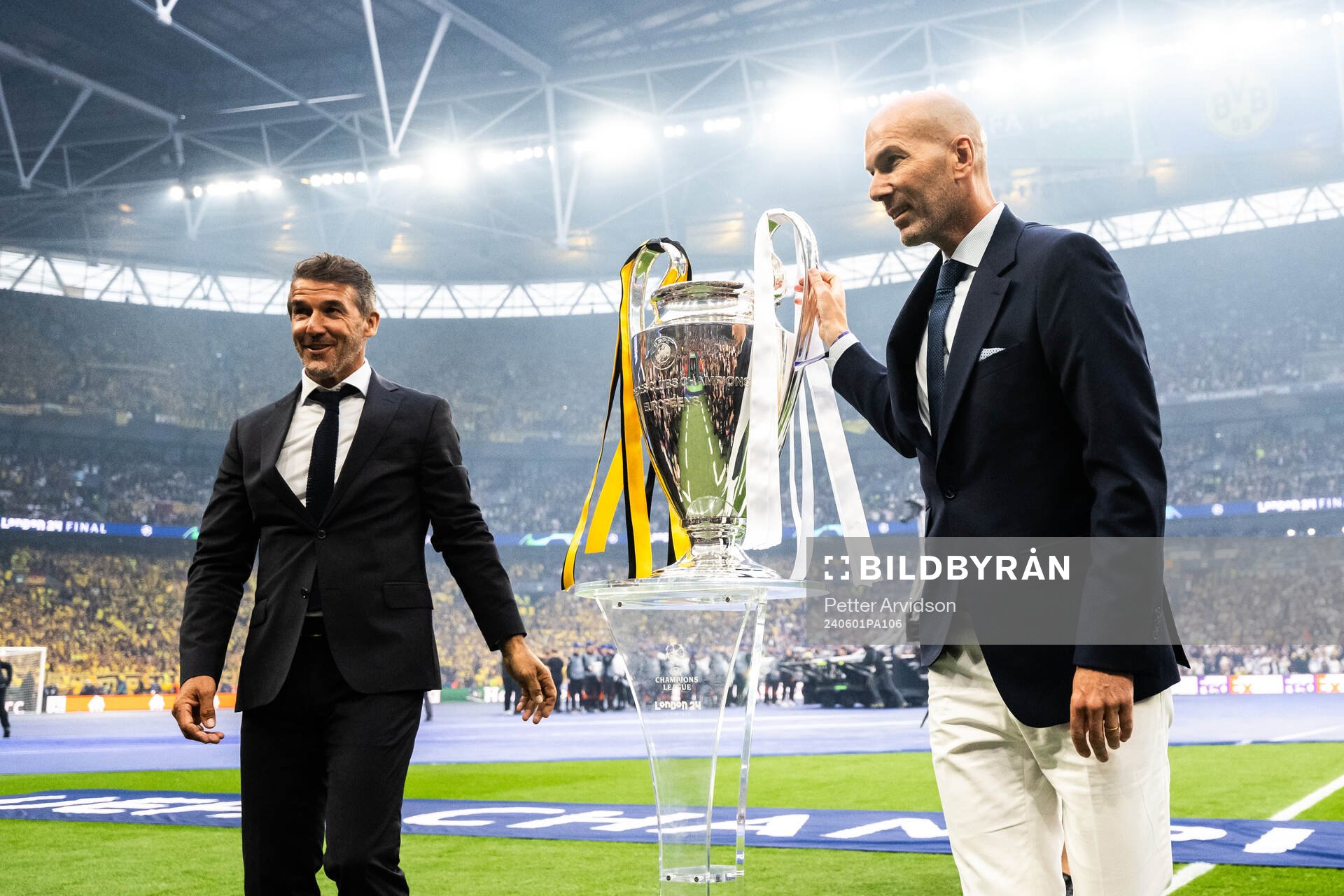 Former players Karl Heinz Riedle and Zinedine Zidane carry the Champions League trophy onto the pitch ahead of the UEFA Champions League final between Dortmund and Real Madrid on June 1, 2024 in London.