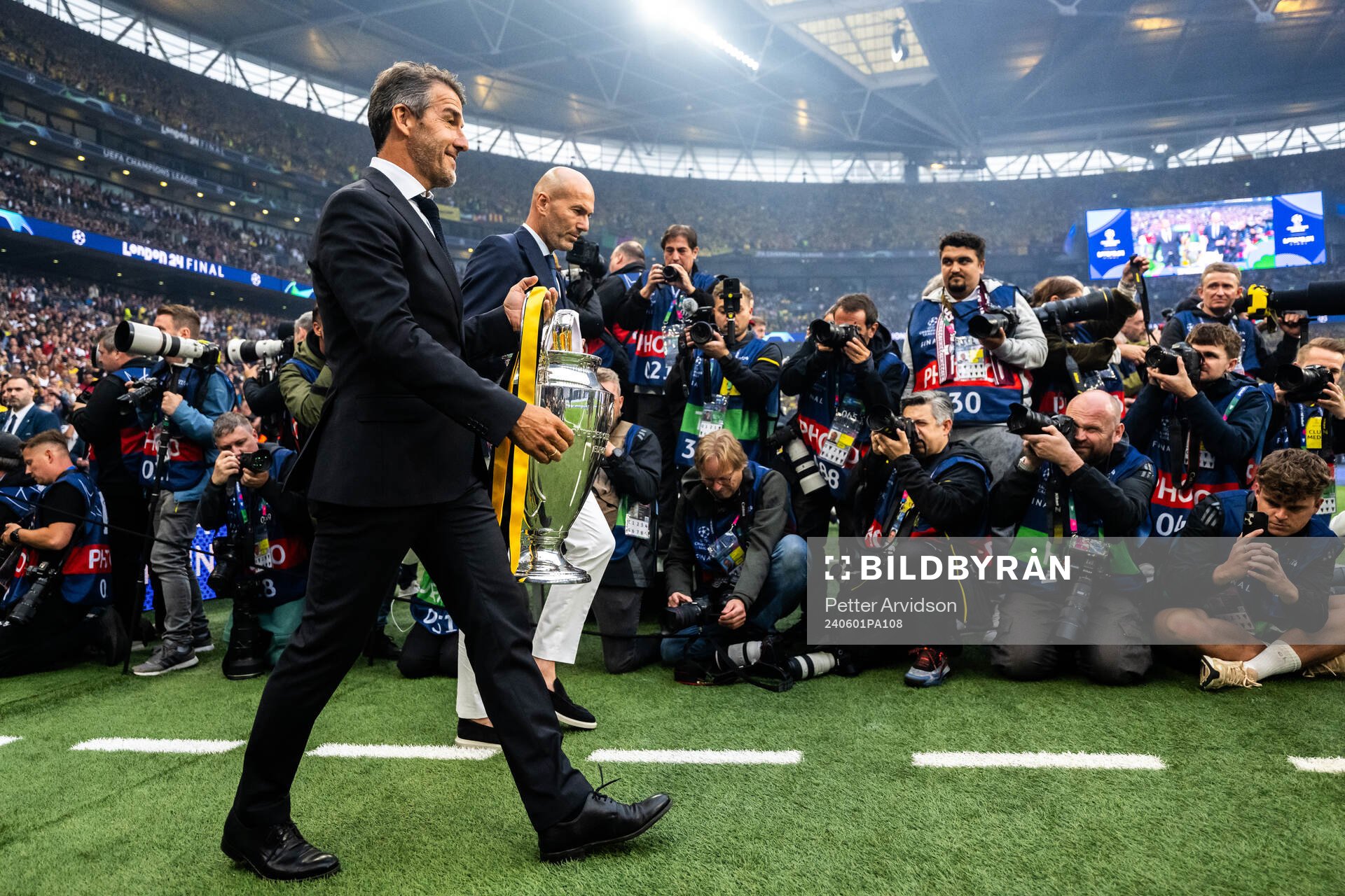 Former players Karl Heinz Riedle and Zinedine Zidane carry the Champions League trophy onto the pitch ahead of the UEFA Champions League final between Dortmund and Real Madrid on June 1, 2024 in London.