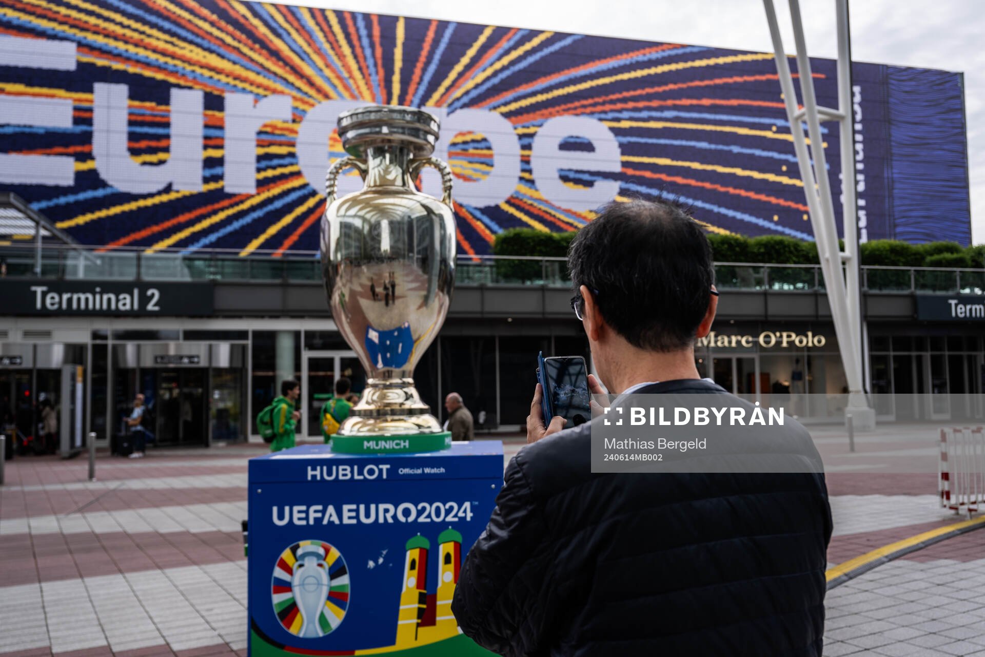 A man takes a photo of a sign with a trophy replica