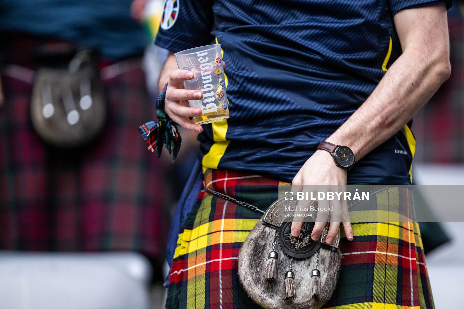 A man in a kilt holding a beer