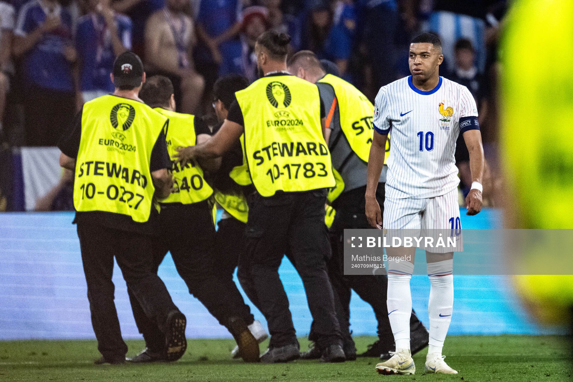 Stewards take care of a pitch invader next to Kylian