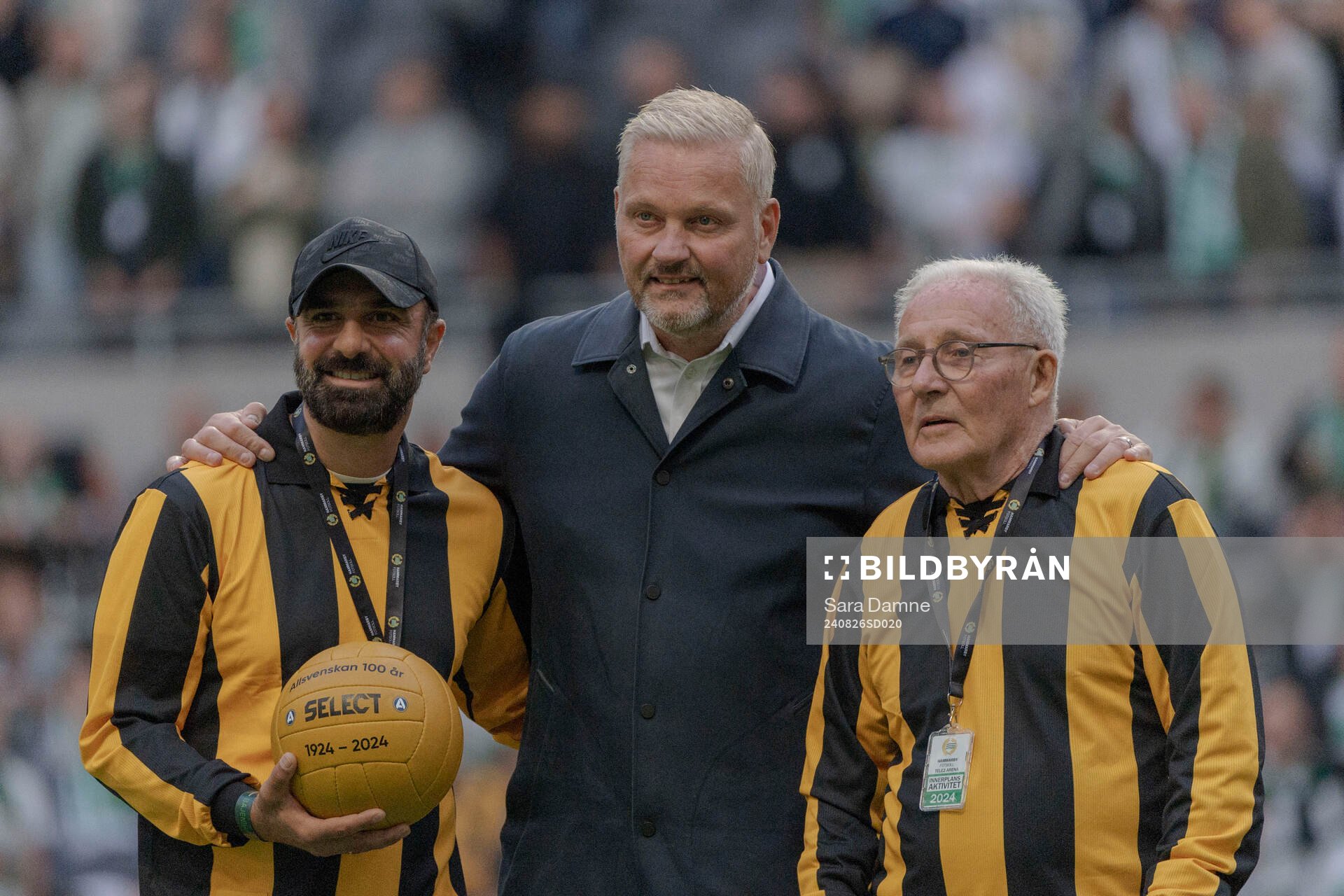 Kennedy Bakircioglu och Kenneth Ohlsson, före detta spelare i Hammarby, tar emot en jubileumsboll av Johan Lindwall, generalsekreterare på SEF, inför fotbollsmatchen i Allsvenskan mellan Hammarby och GAIS den 26 augusti 2024 i Stockholm.