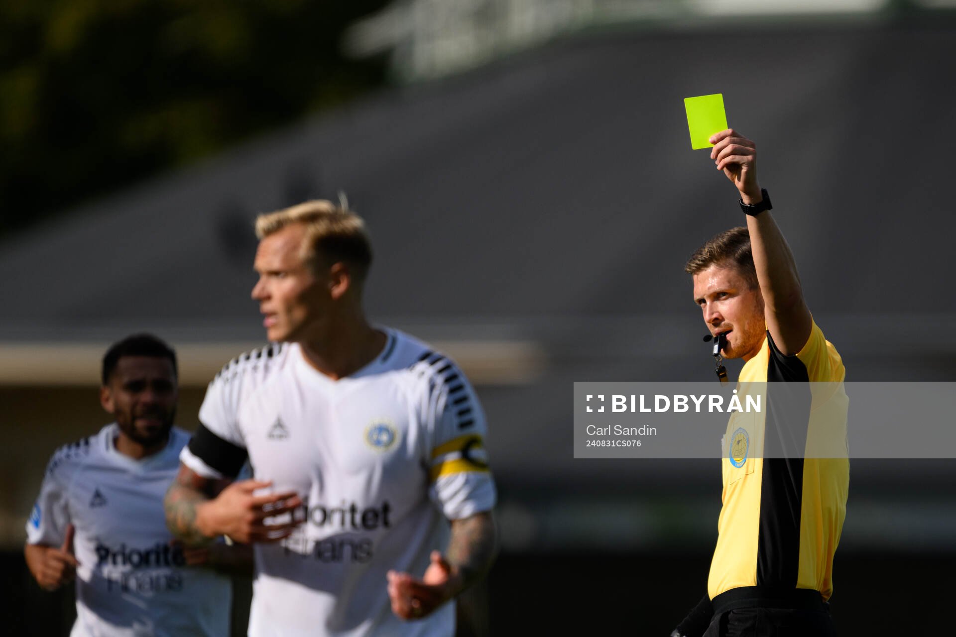 Domare Erik Mattsson delar ut ett gult kort