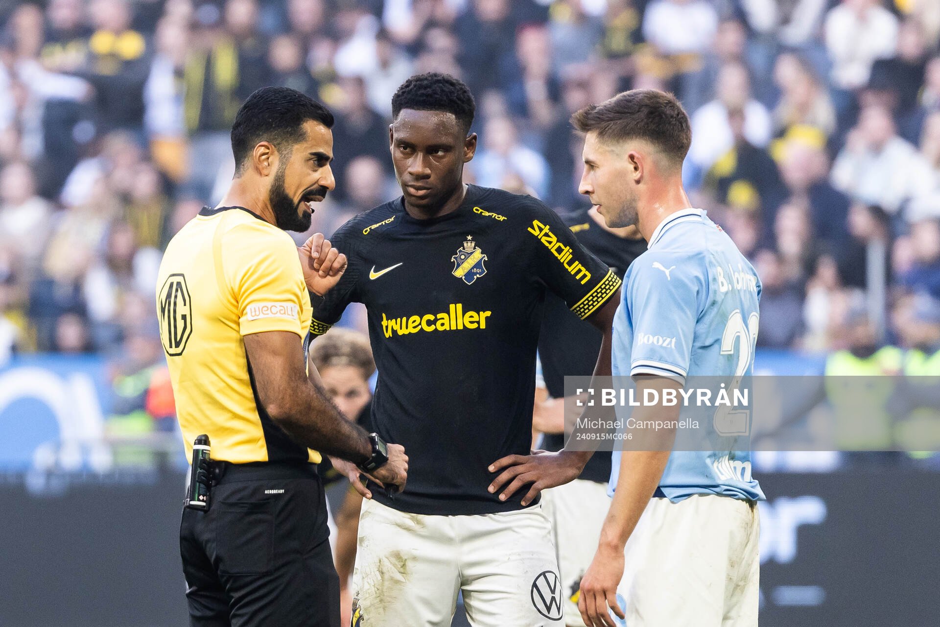 Domare Mohammed Al-Hakim i samtal med AIKs Mouhamed Lamine Fanne Dabo och Malmö FFs Lasse Berg Johnsen under fotbollsmatchen i Allsvenskan mellan AIK och Malmö FF den 15 september 2024 i Stockholm.
