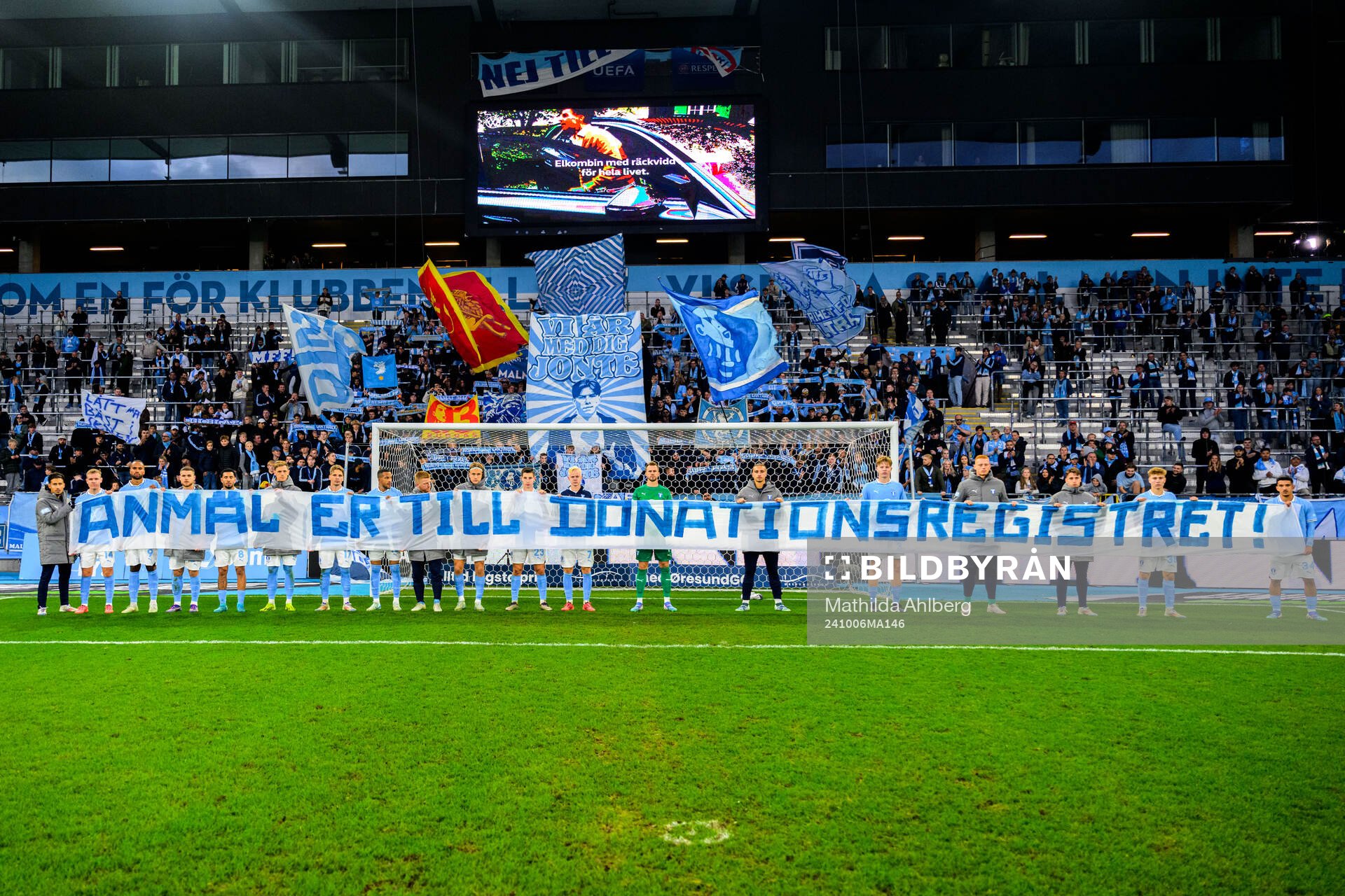 Malmö FF spelare med banderoll framför klacken