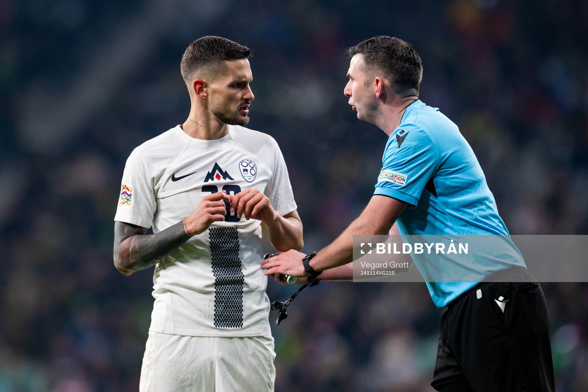 Petar Stojanovic of Slovenia and referee Michael Oliver