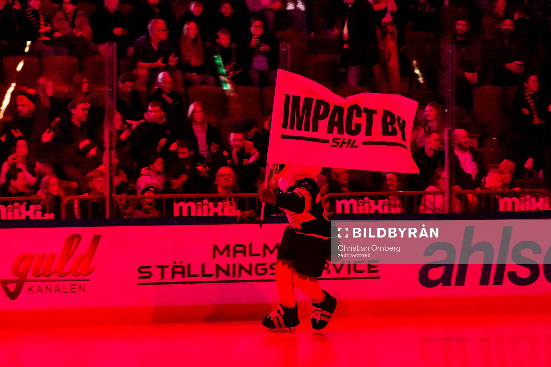 Malmö Redhawks maskot Hawkan med en Impact by SHL-flagga