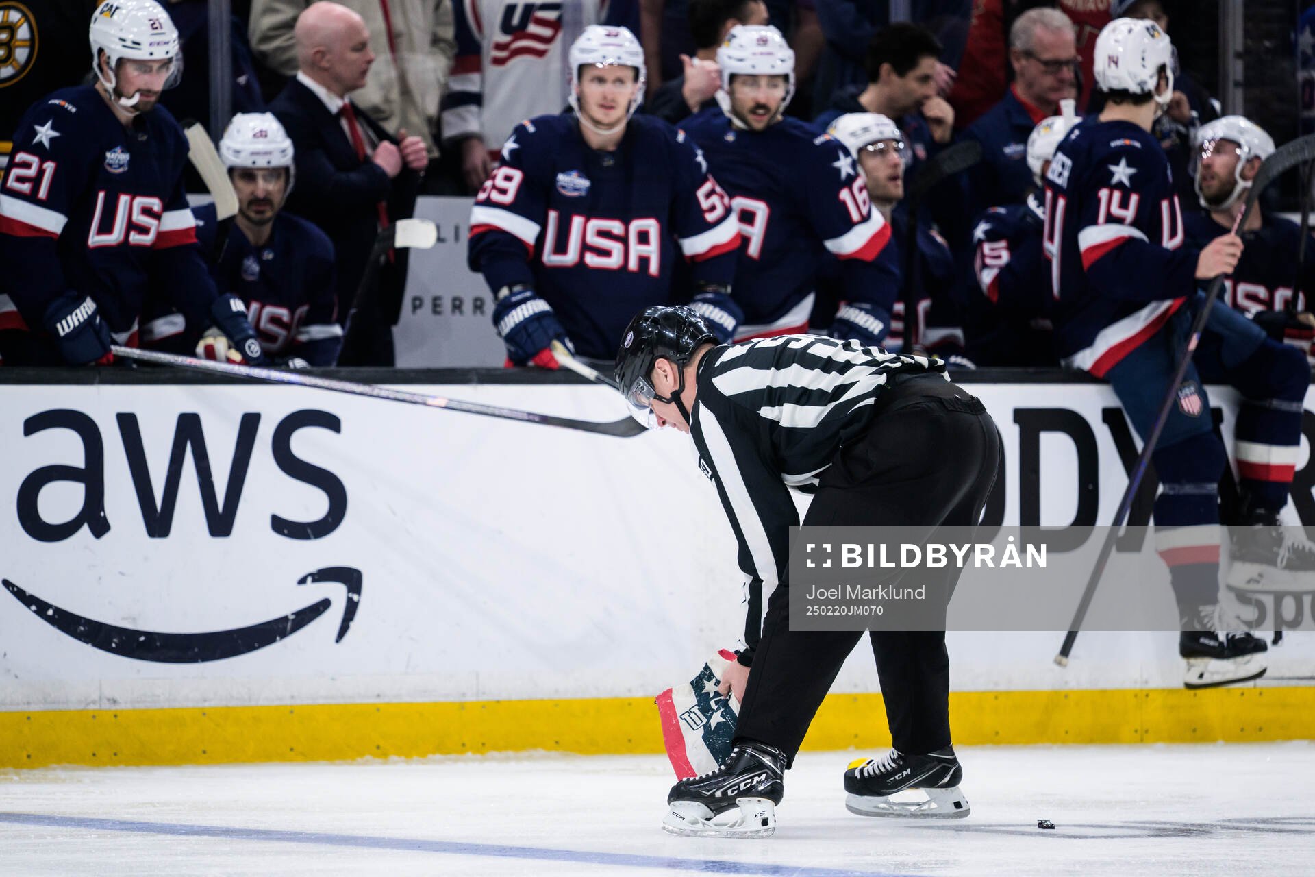 A linesman picks up an item that was thrown onto the ice