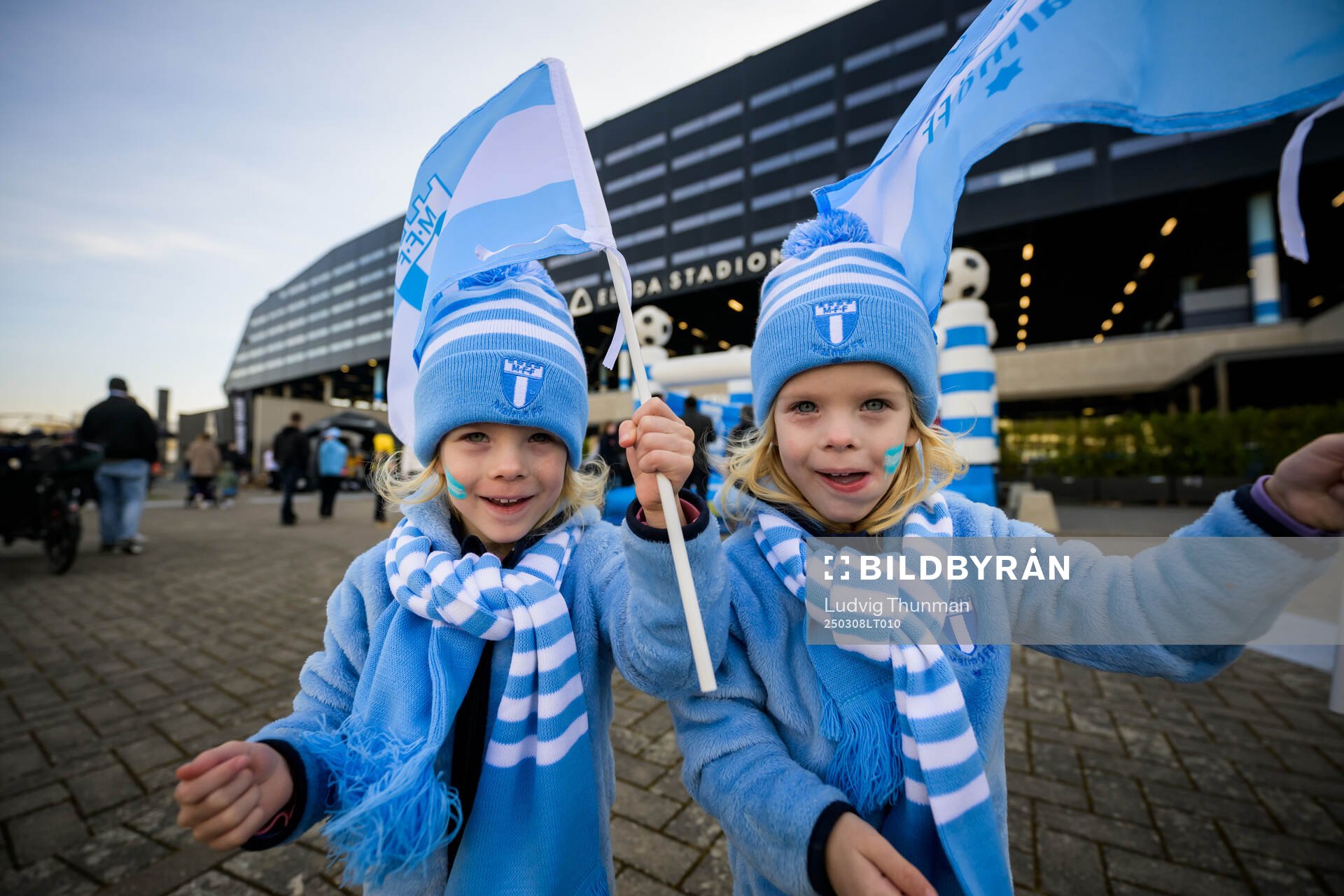 Två barn klädda i Malmö FFs mössa, halsduk och tröjor