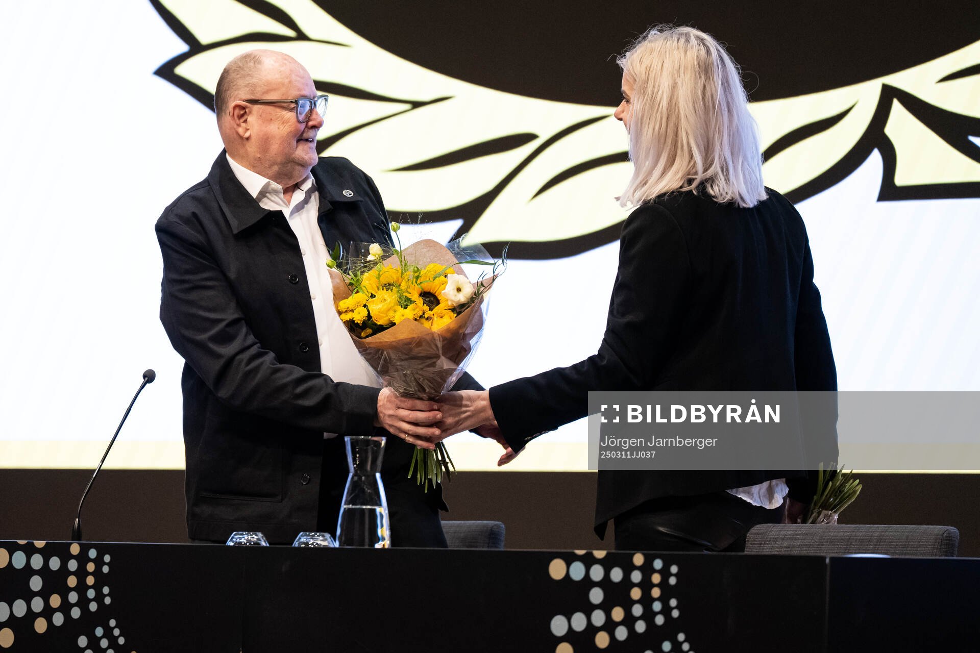 Mötesordförande Pelle Höög får blommor av ekonomichef
