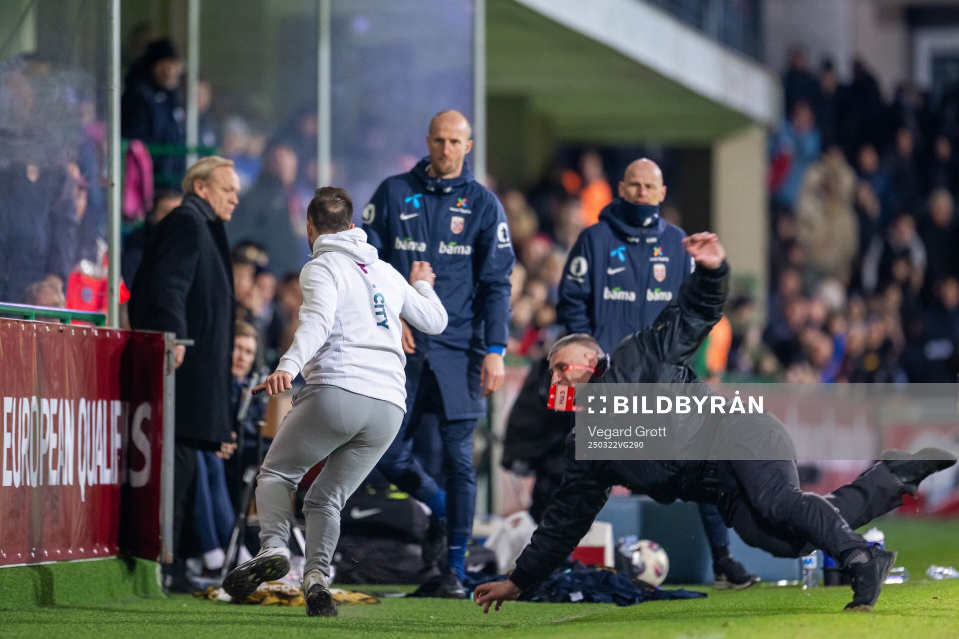A pitch invader runs towards the bench of Norway