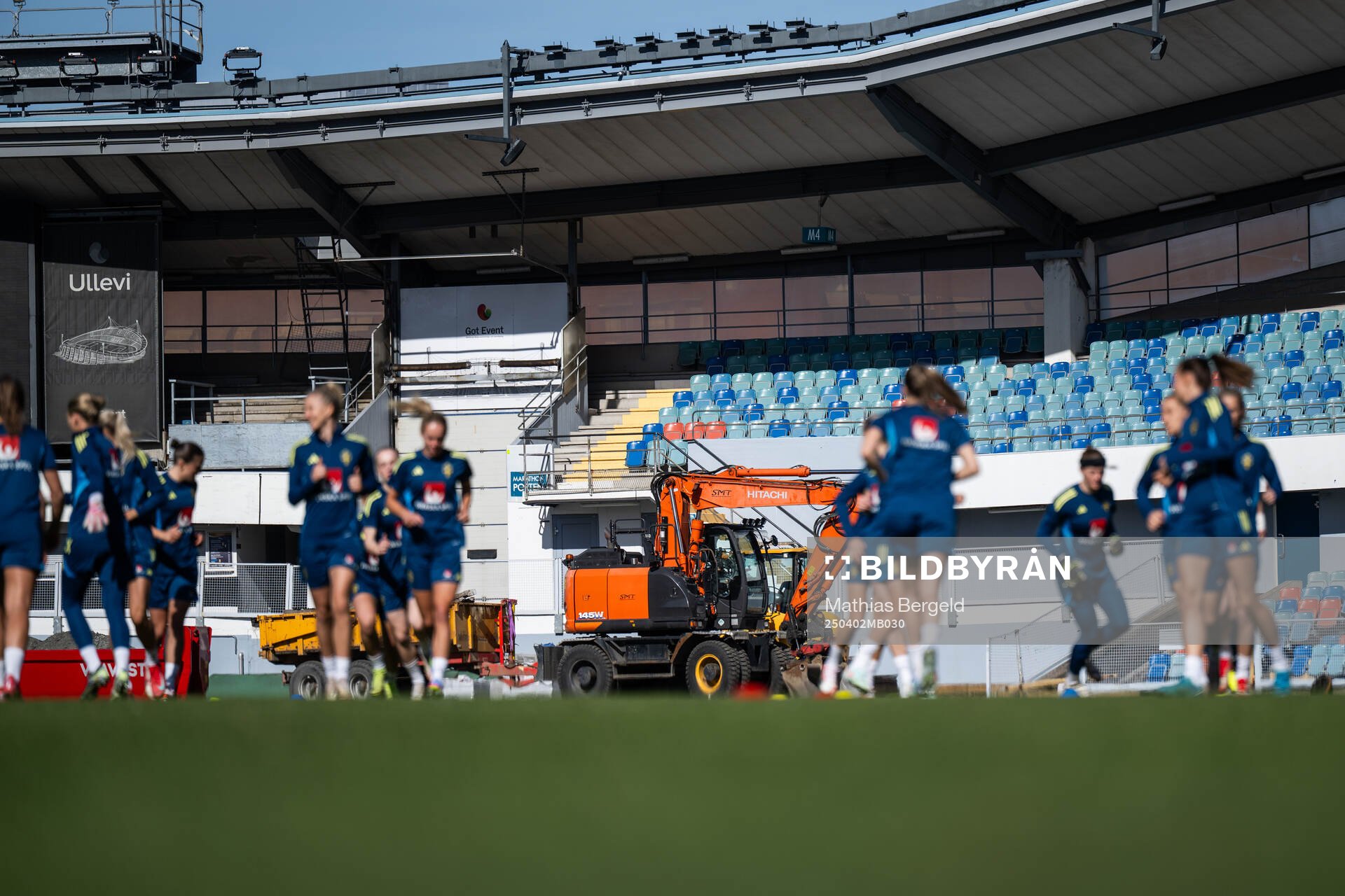 An excavator is seen behind players