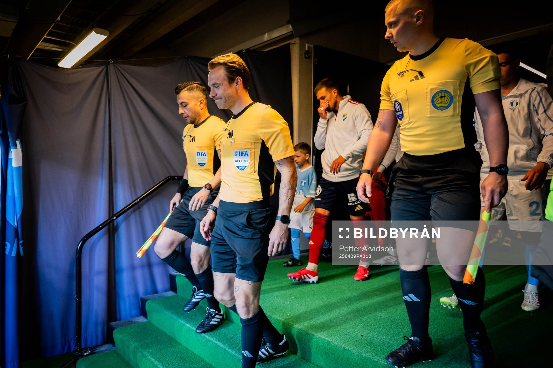 Fotbollsdomaren Kristoffer Karlsson gör entré ihop med, till vänster linjedomare Mahbod Beigi och till höger linjedomare Anton Sjöberg inför fotbollsmatchen i Allsvenskan mellan Malmö FF och Öster den 29 april 2025 i Malmö.
