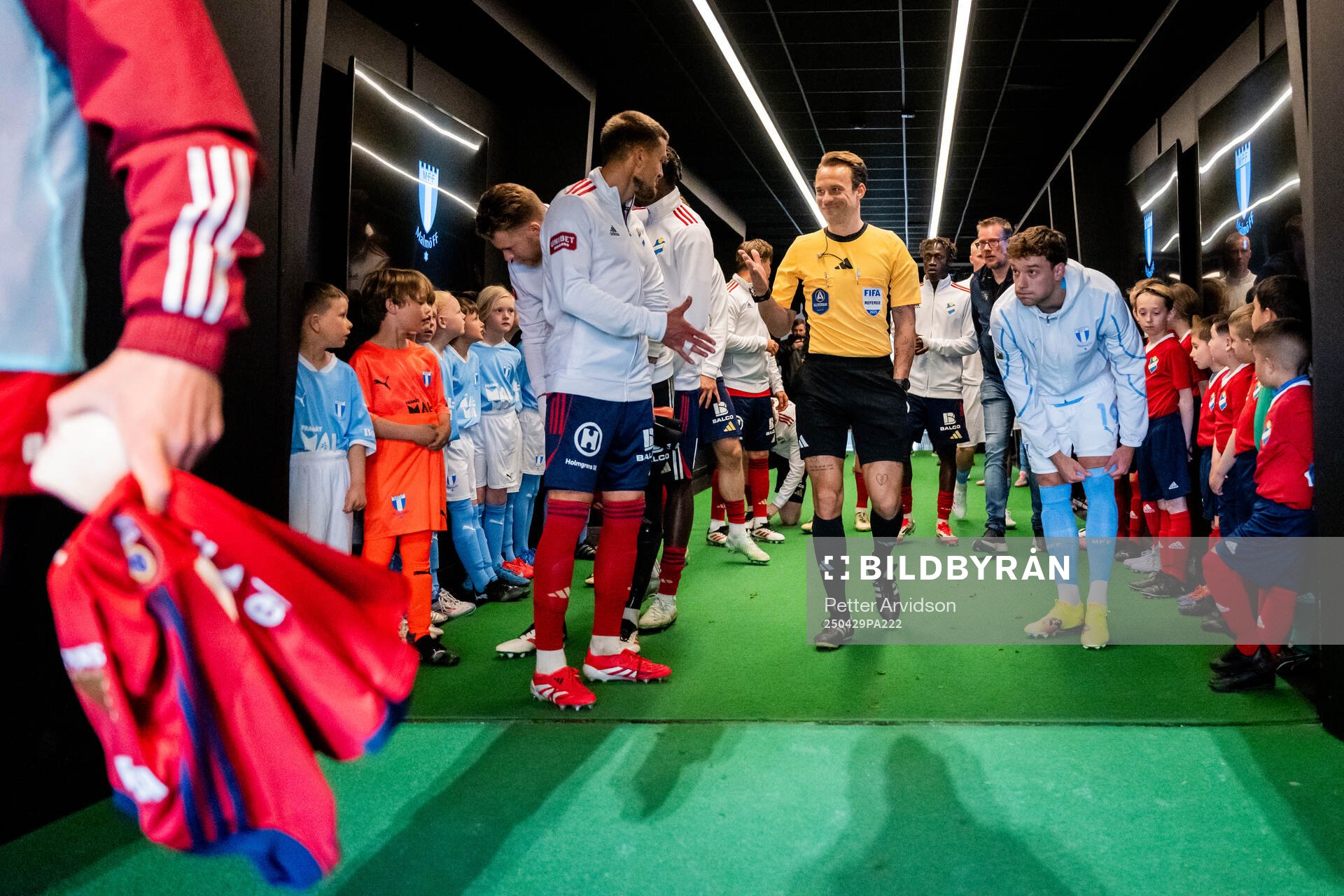 Fotbollsdomaren Kristoffer Karlsson hälsar på Östers Ivan Kricak och till höger står Malmö FFs Colin Rösler i spelargången inför fotbollsmatchen i Allsvenskan mellan Malmö FF och Öster den 29 april 2025 i Malmö.