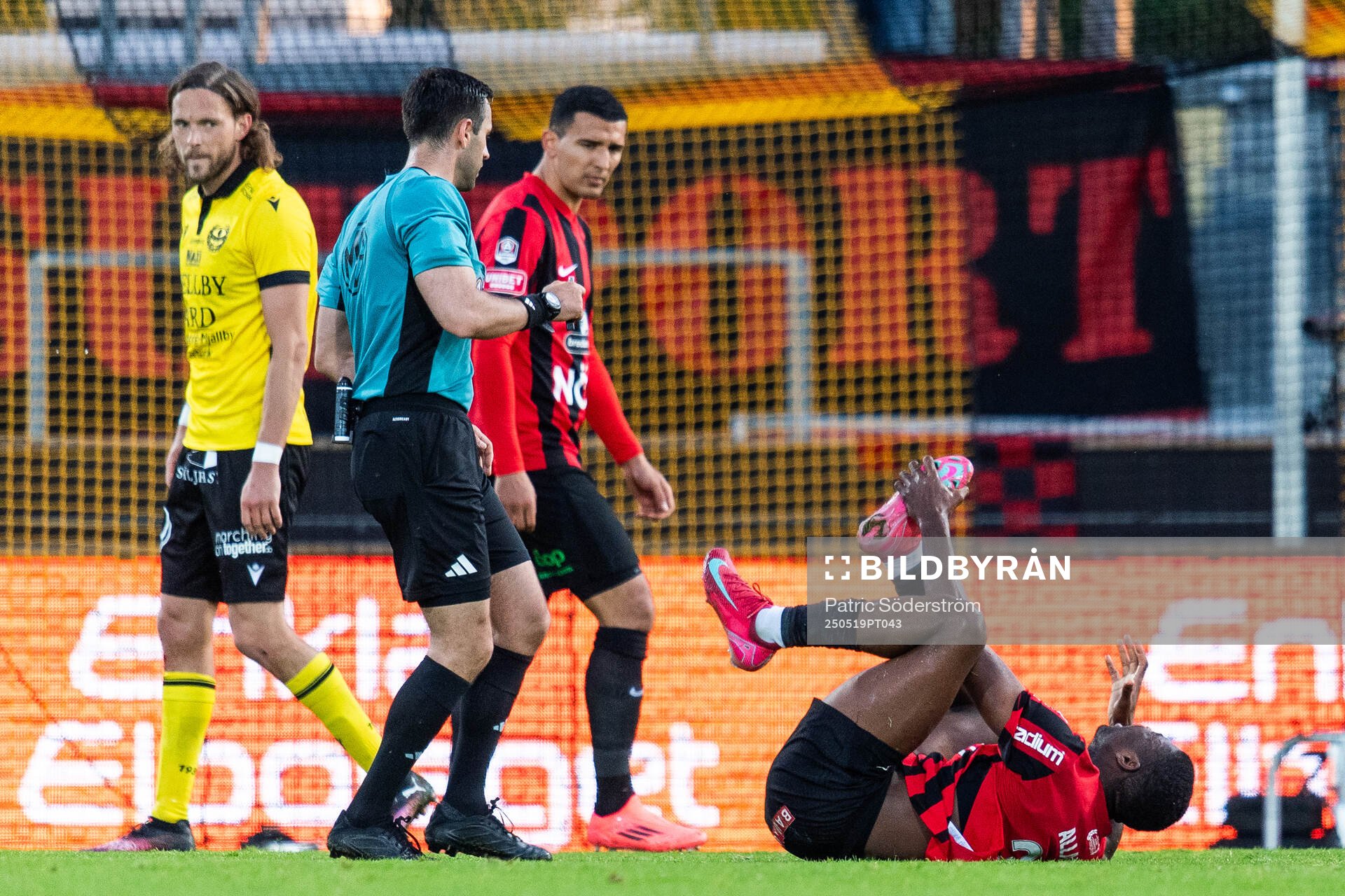 Domare Granit Maqedonci bredvid Brommapojkarnas Ezekiel Alladoh som har ont under fotbollsmatchen i Allsvenskan mellan Mjällby och Brommapojkarna den 19 maj 2025 i Hällevik.