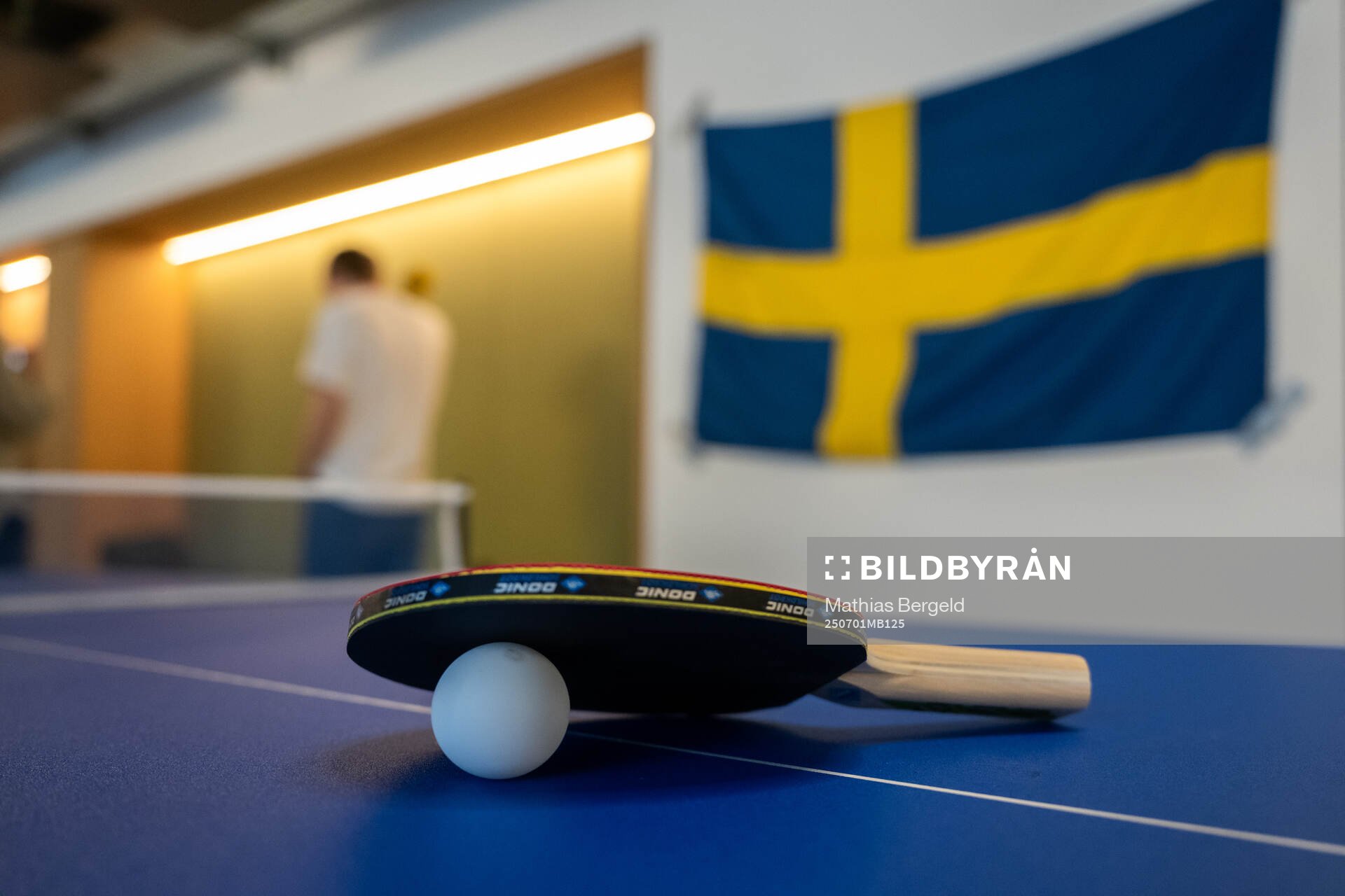 A Table Tennis racket and ball with a Swedish flag behind
