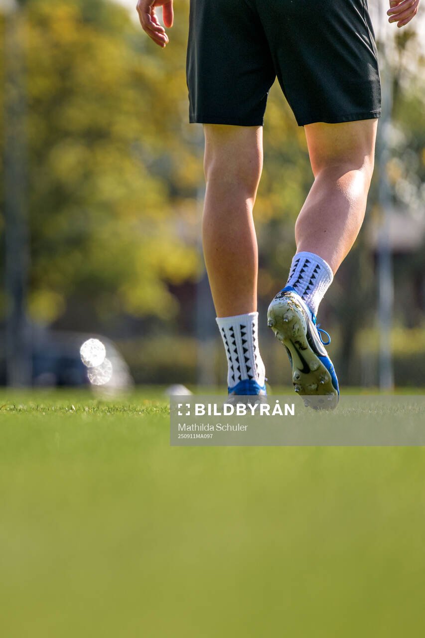 Fötter i fotbollsskor på en fotbollsplan