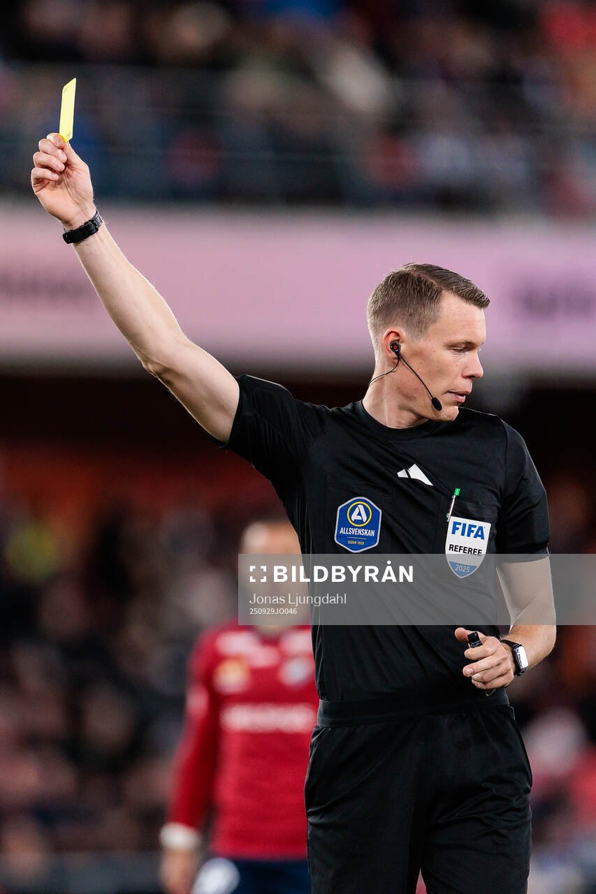 Domare Oscar Johnson delar ut ett gult kort