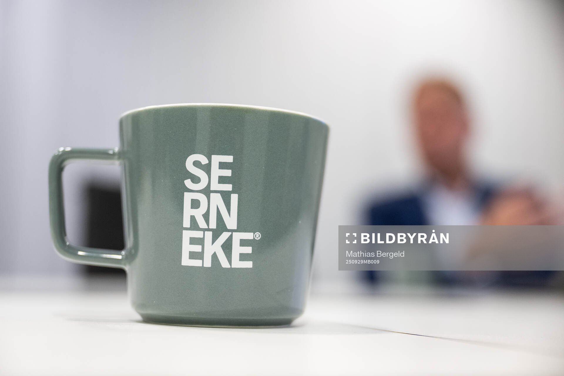 En kaffemugg med texten Serneke och i bakgrunden syns Ola