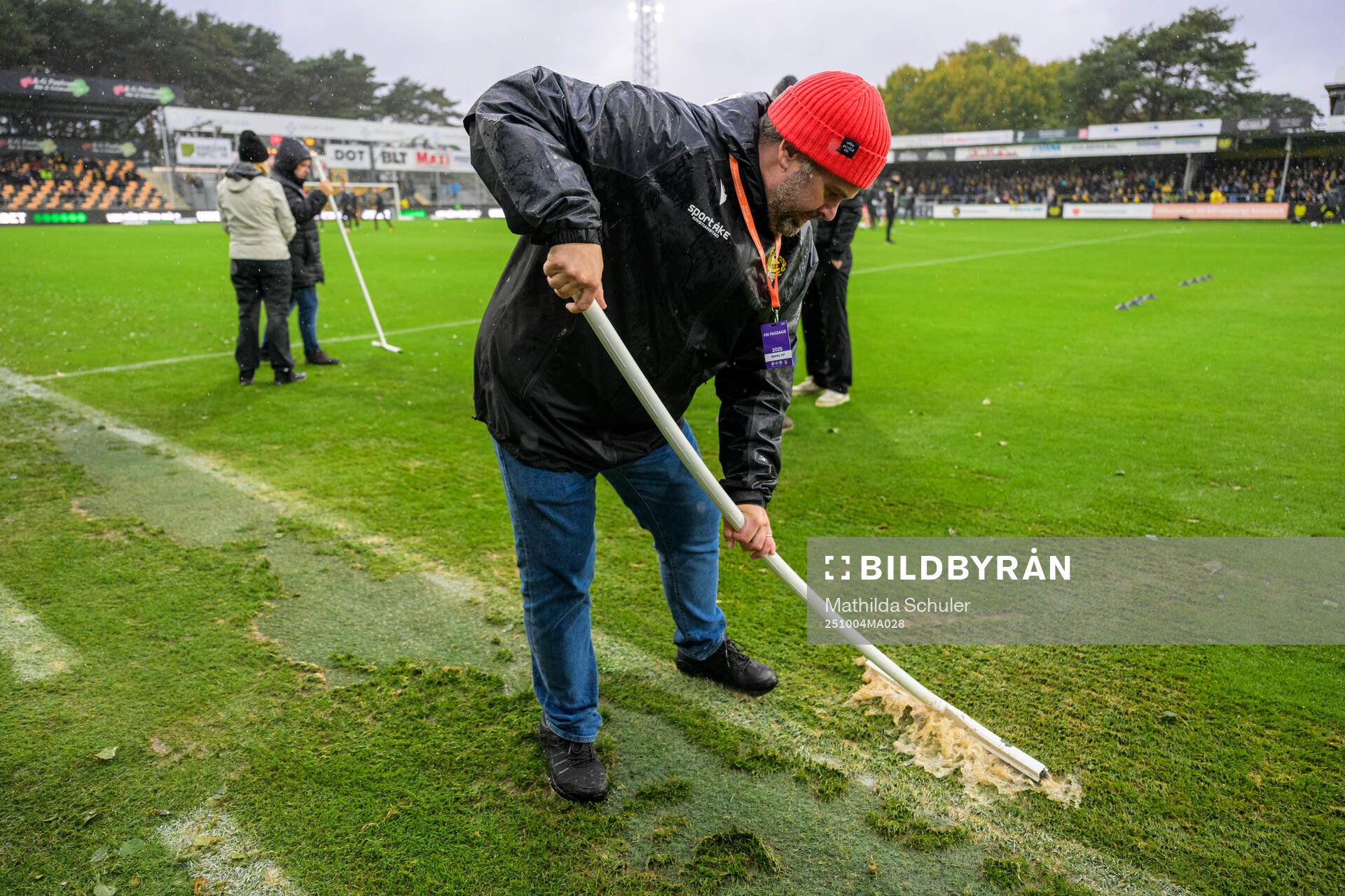 Funktionärer skrapar bort vatten från planen
