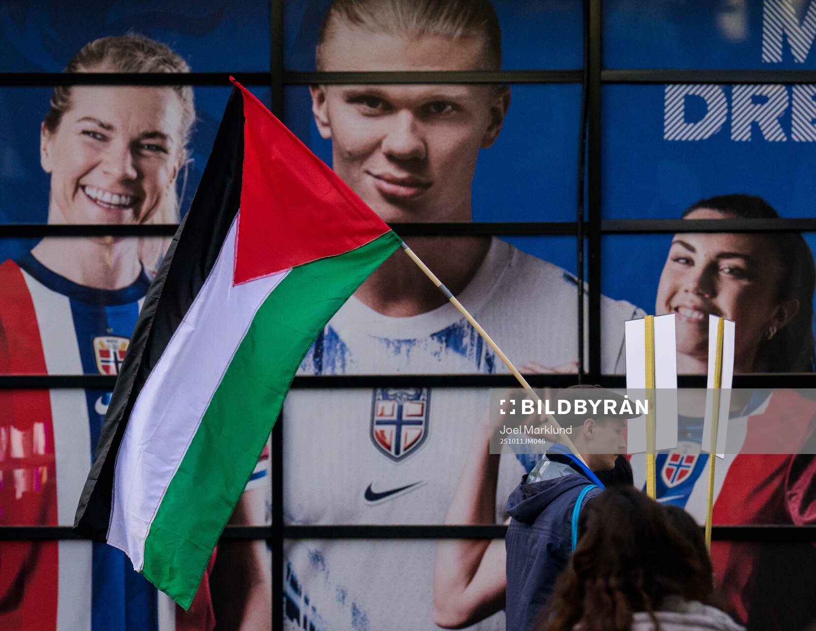 A Palestinian protester walks past a collage showing