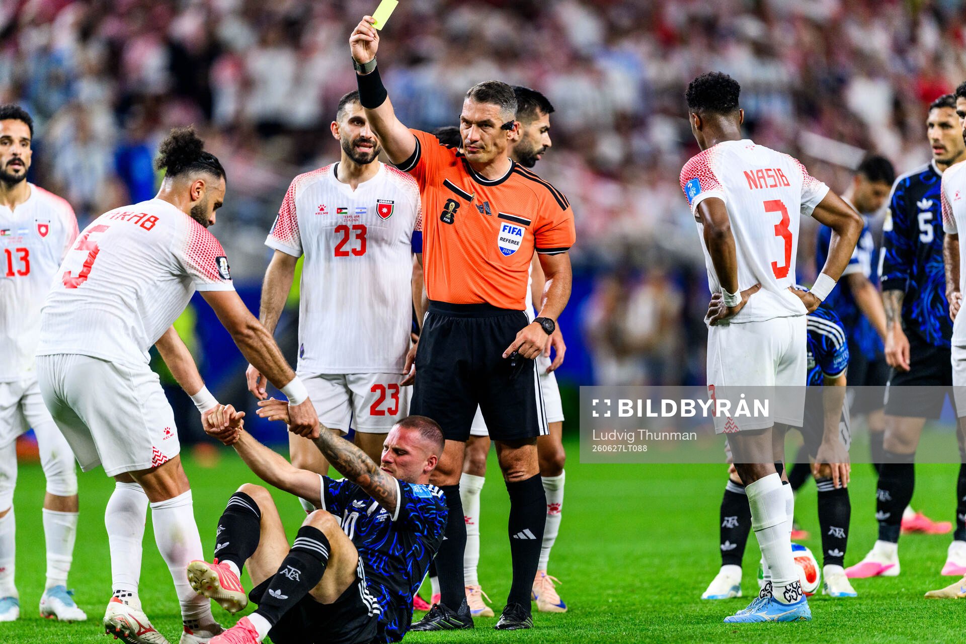 Referee Istvan Kovacs calls a yellow card and Yazan Alarab